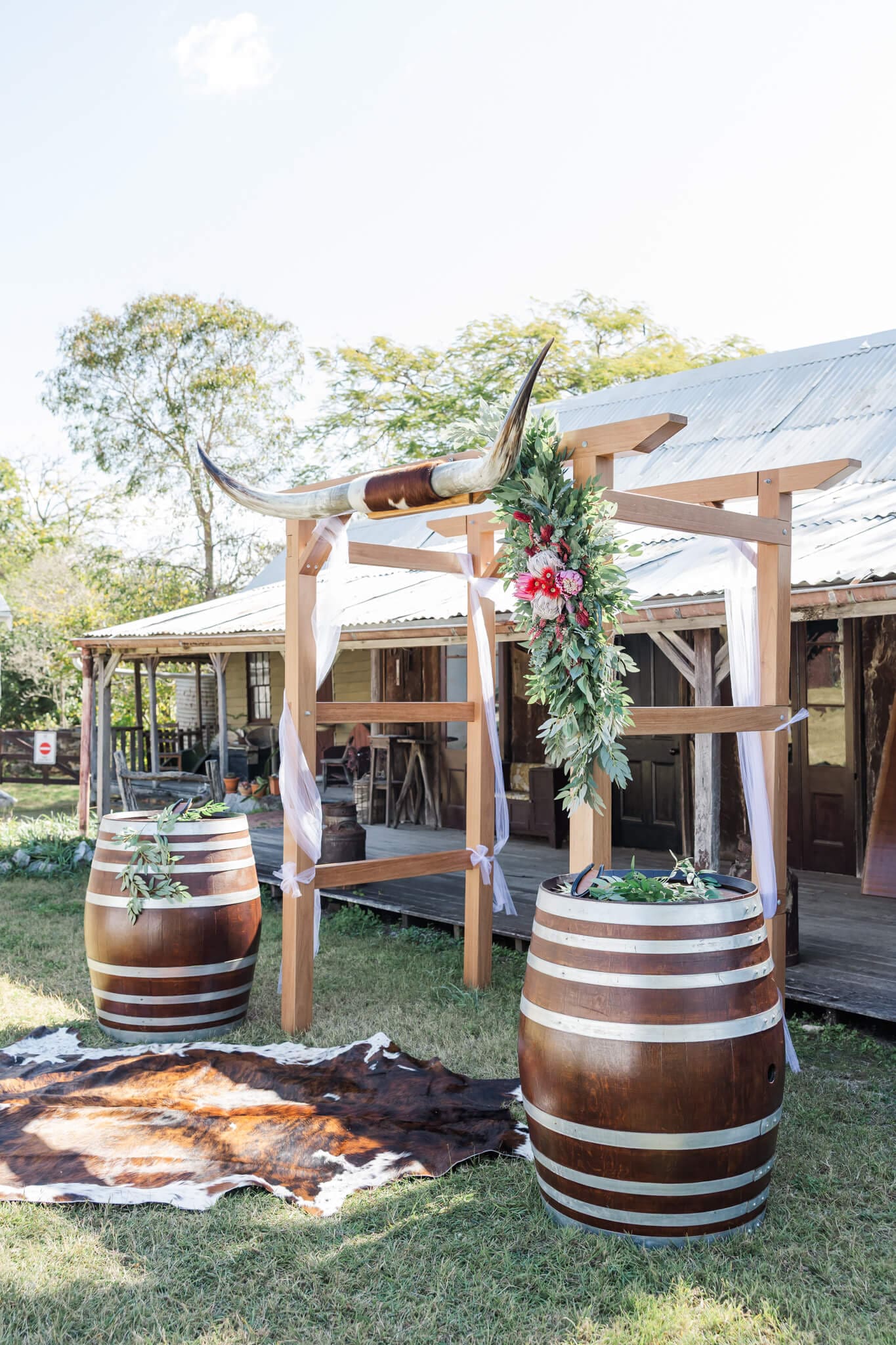 Wedding ceremony set up with a wedding arbor, white guest chairs and two barrels to emphasize the rustic look.