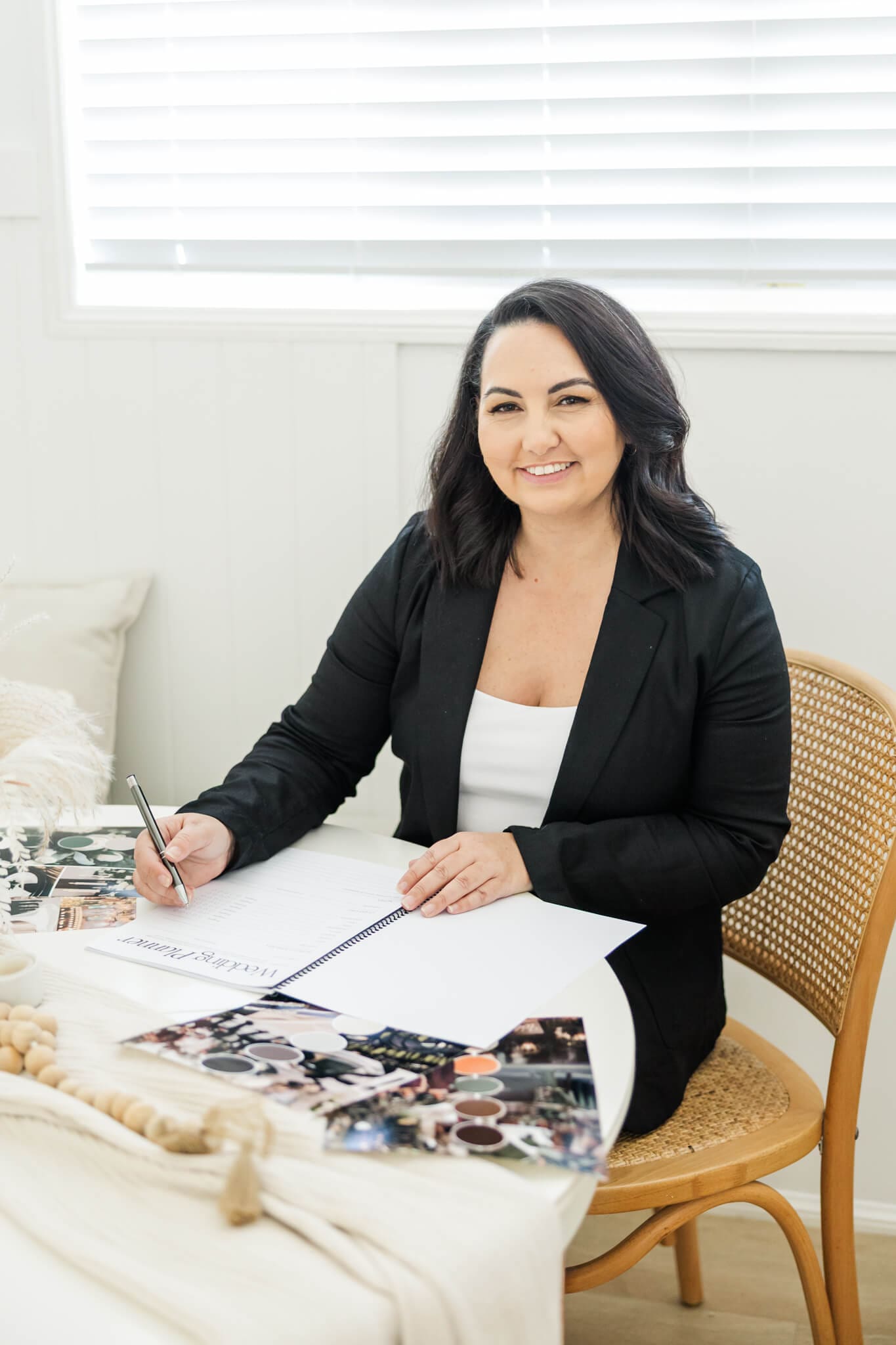 An event planner shows her skills as a wedding planner. Seated at a table with a schedule and books for her work.