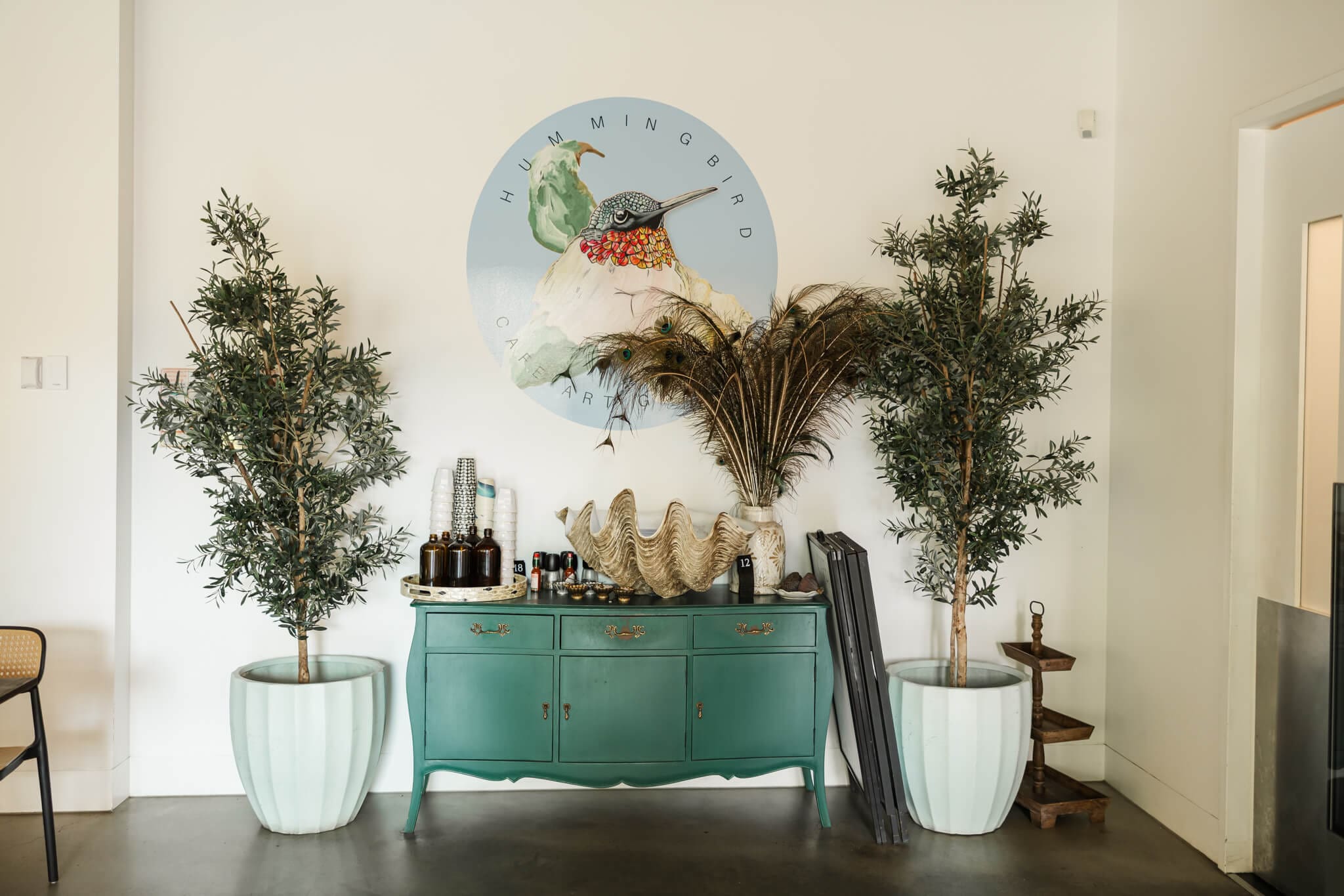 Hummingbird Cafe entrance in Rockhampton featuring a large hummingbird clock and peacock feathers..