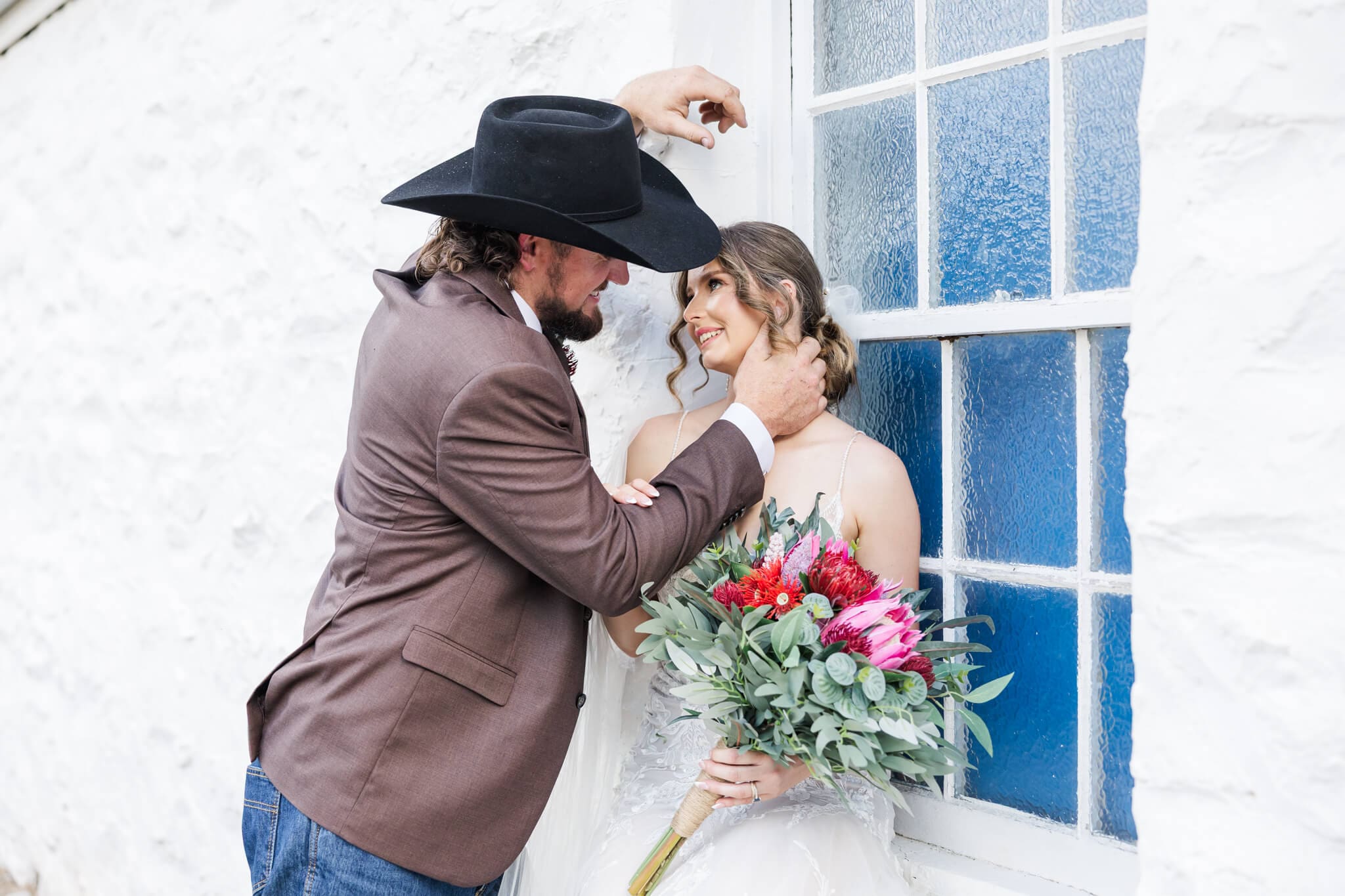 Bride and Groom share a quiet moment as the groom leans in towards his wife while she sits on a window ledge. Captured by Rockhampton Photographer Julie-Anne Photography.