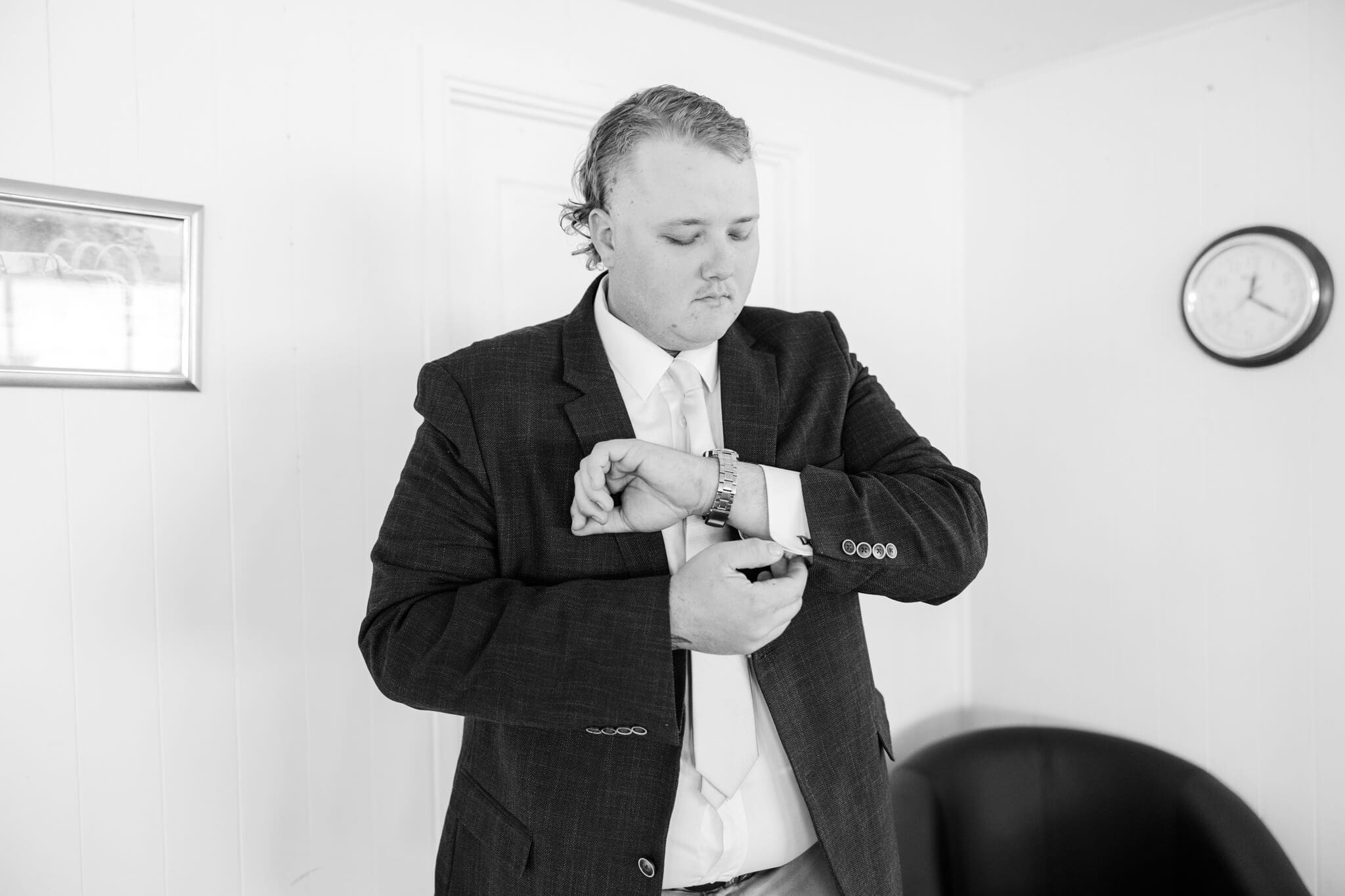 Groom adjusts his cuff and cuff links as he prepares for his wedding day.