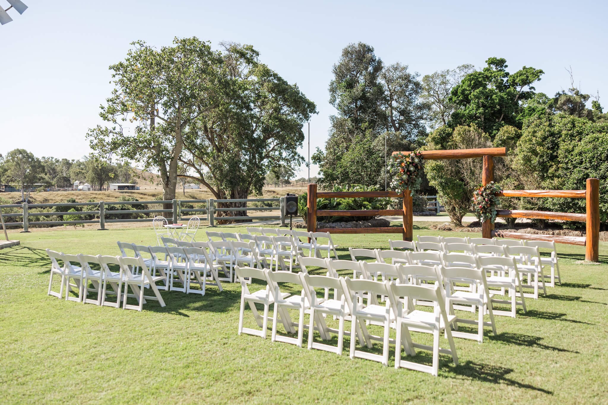 Ceremony set up at The Old Station Raglan featuring wooden yards decorated with native florals.