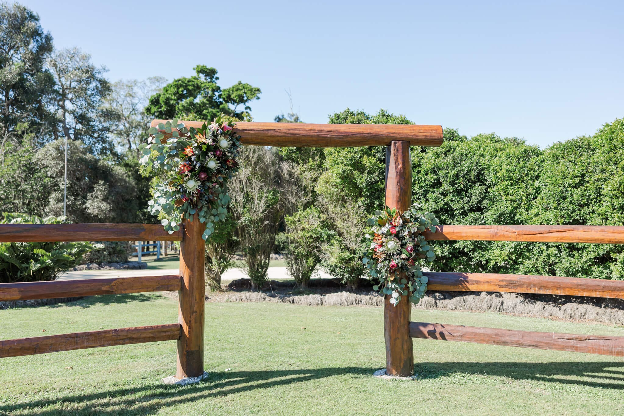 Ceremony set up at The Old Station Raglan featuring wooden yards decorated with native florals.