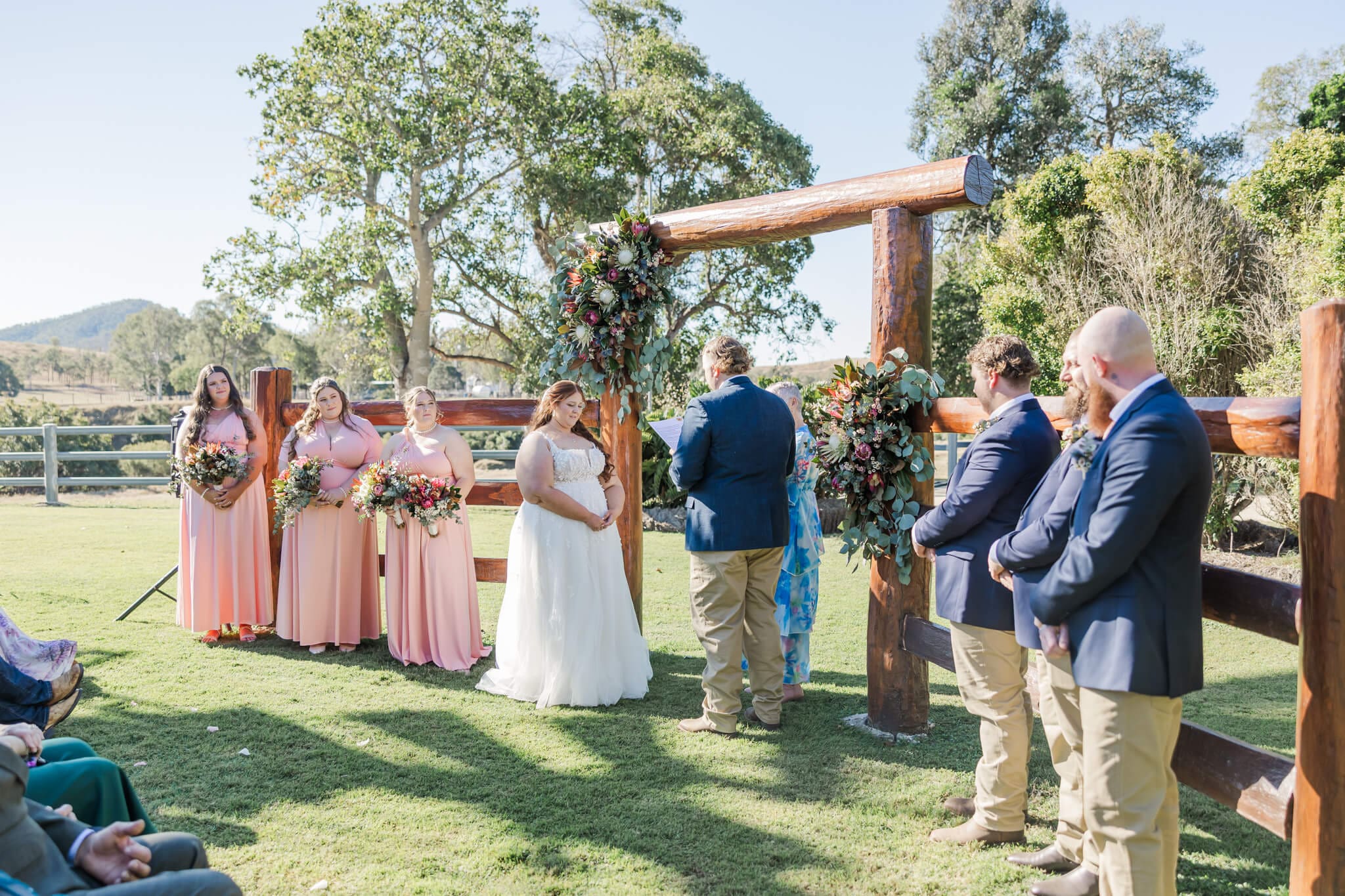 Wedding ceremony at the Old Station Raglan, as the bride and groom exchange vows with their bridal party, in front of yards feature.