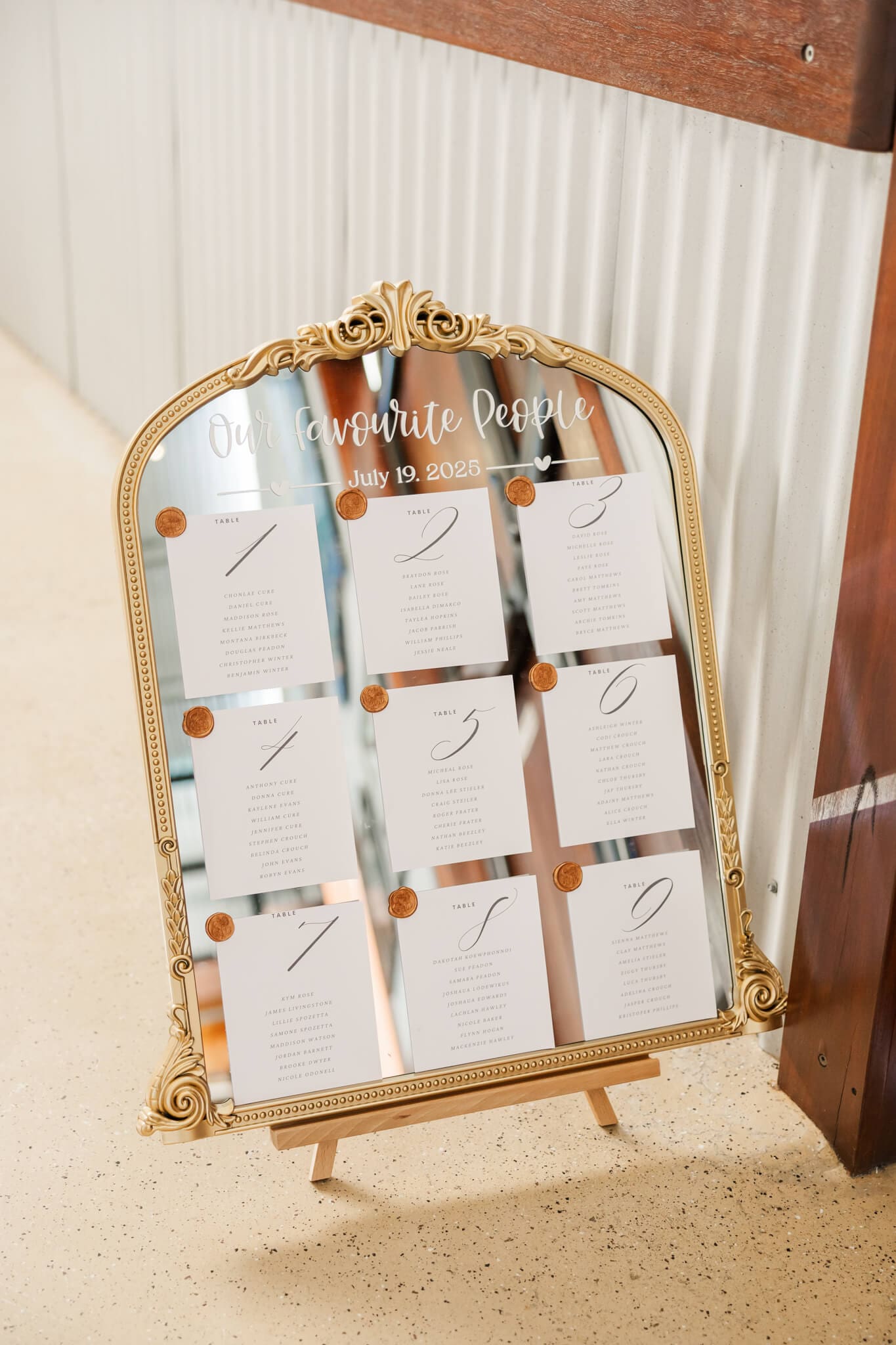 A gold mirror featuring the seating positions for a wedding reception.