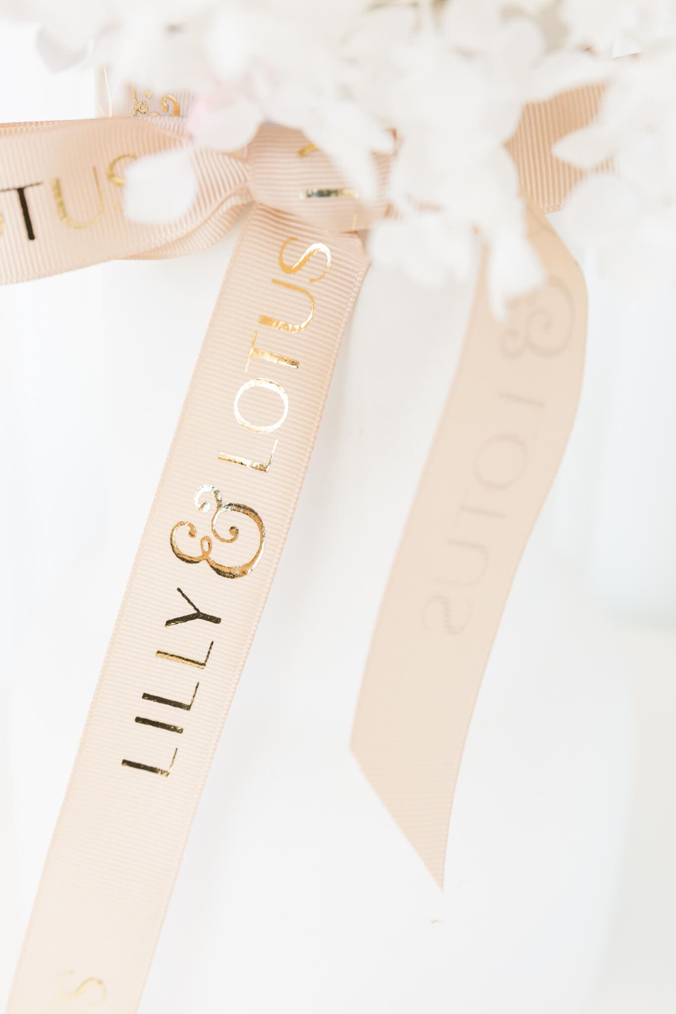 Detail shot of a Lilly and Lotus pink ribbon with gold writing.