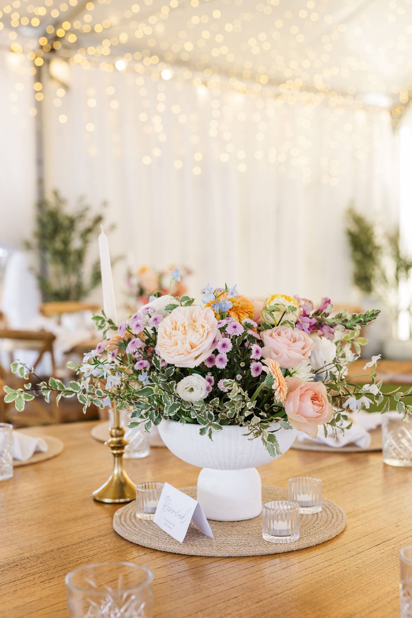 Beautiful detail photo at a wedding reception of a vase with a large bouquet of flowers as a centre piece on a table.