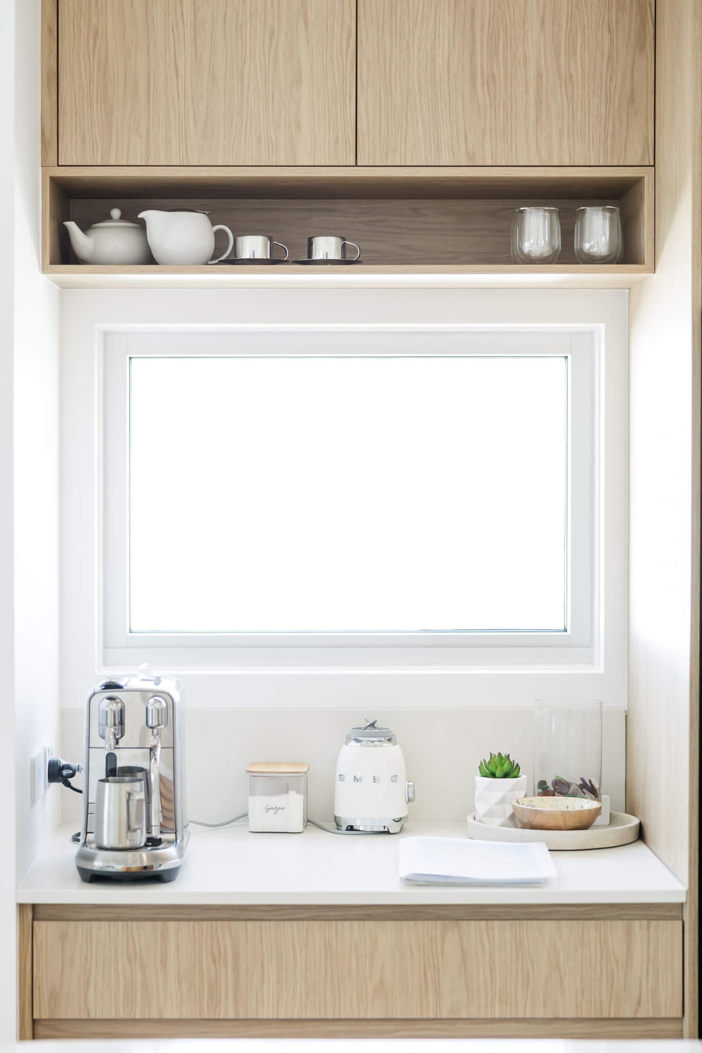 Detailed kitchen shot taken by an Airbnb Photographer near Yeppoon. The white bench has a coffee machine, sugar bowl and some plants to decorate the space.