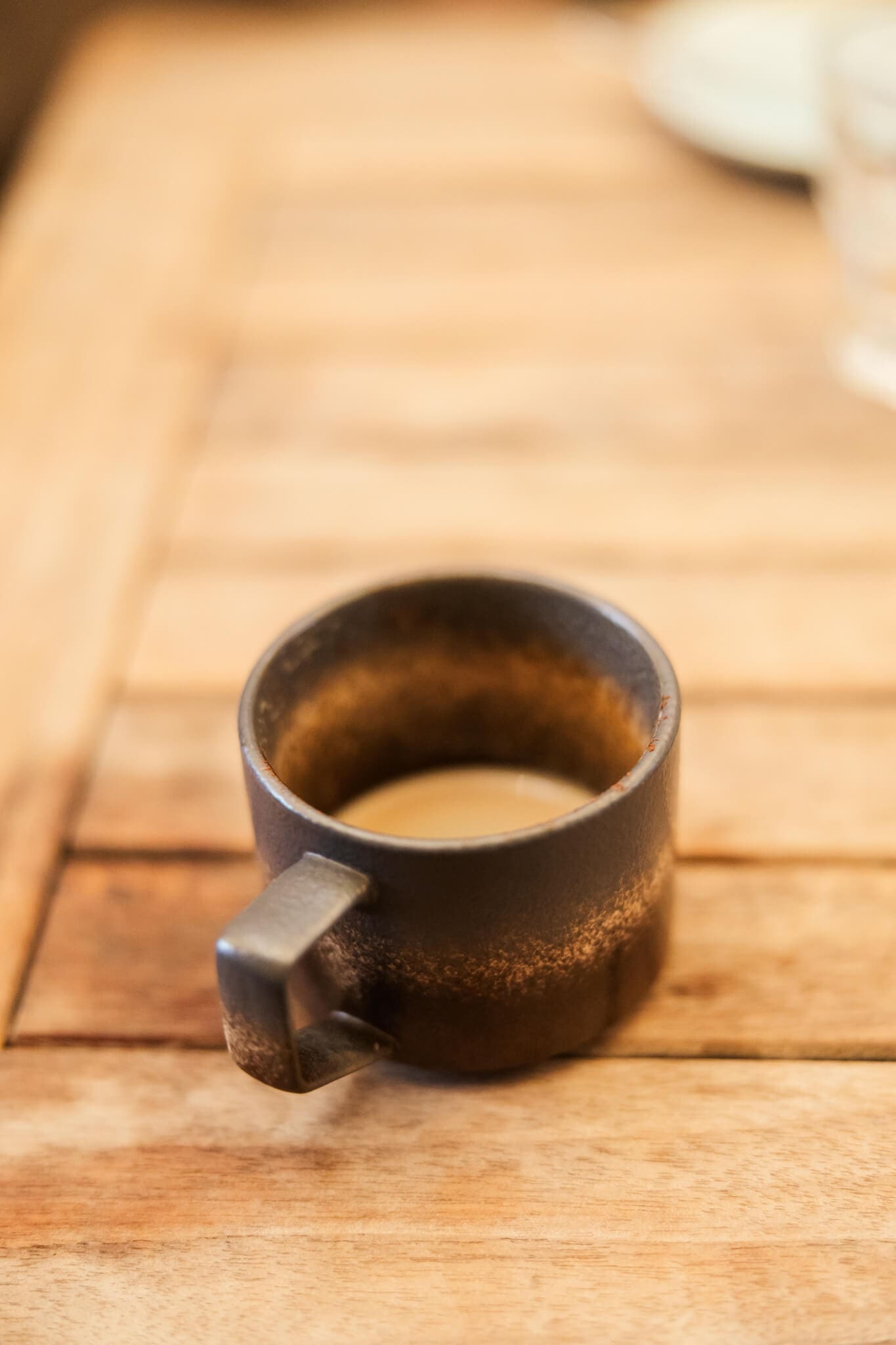 Detail shot of a brown mug of a coffee that is nearly empty.