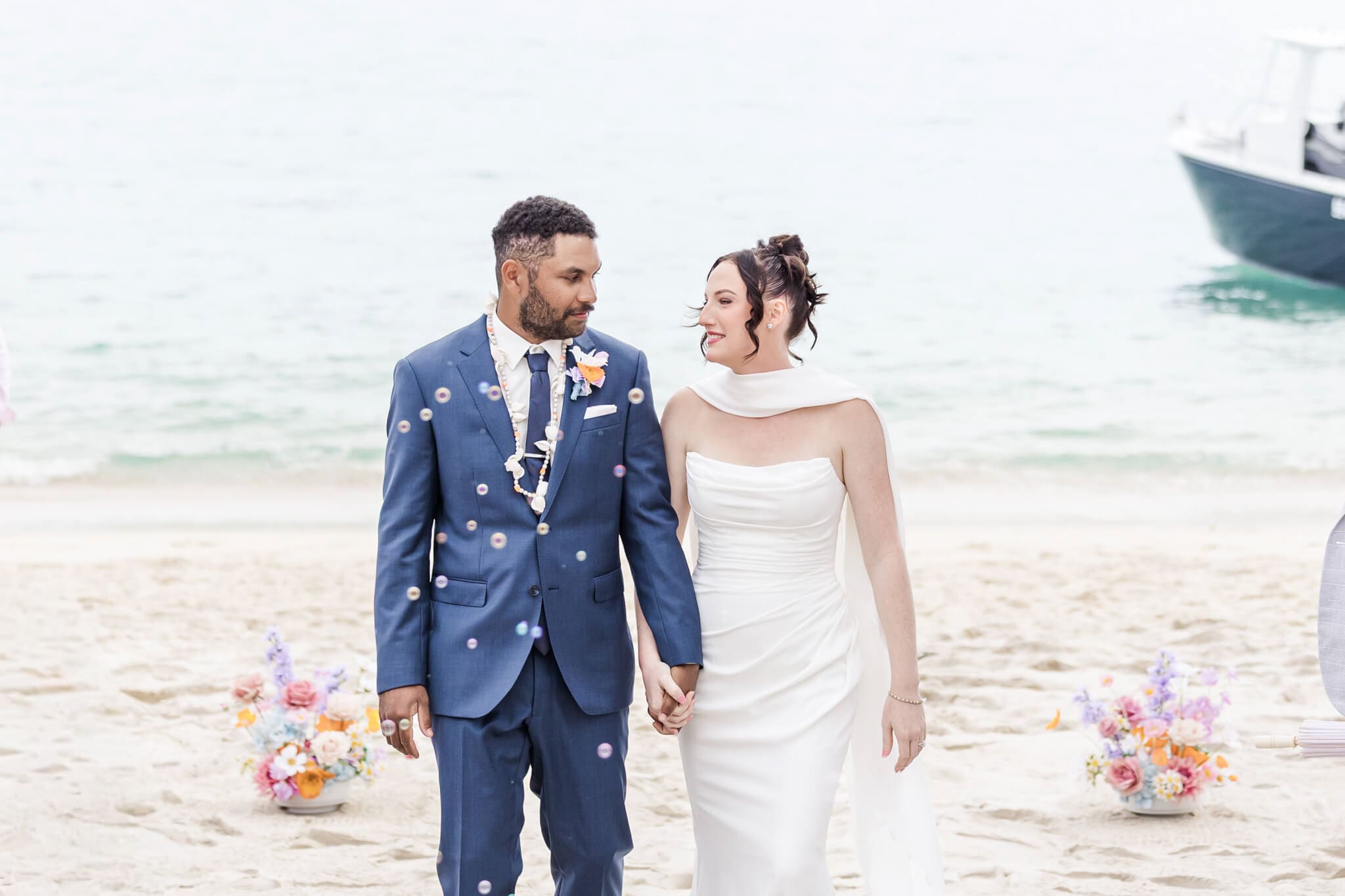 Bride and Groom walk through rose petal confetti. Captured by Julie-Anne Photography.