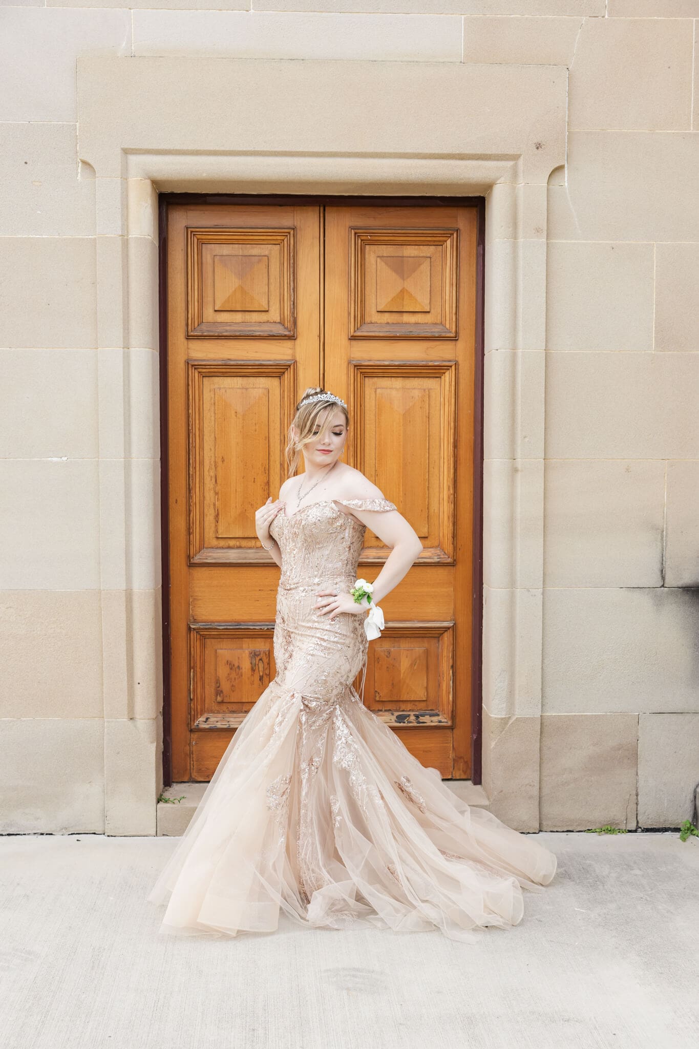Beautiful girl in her formal graduation dress, posing in front of an orange door. Formal dress is a nude colour.