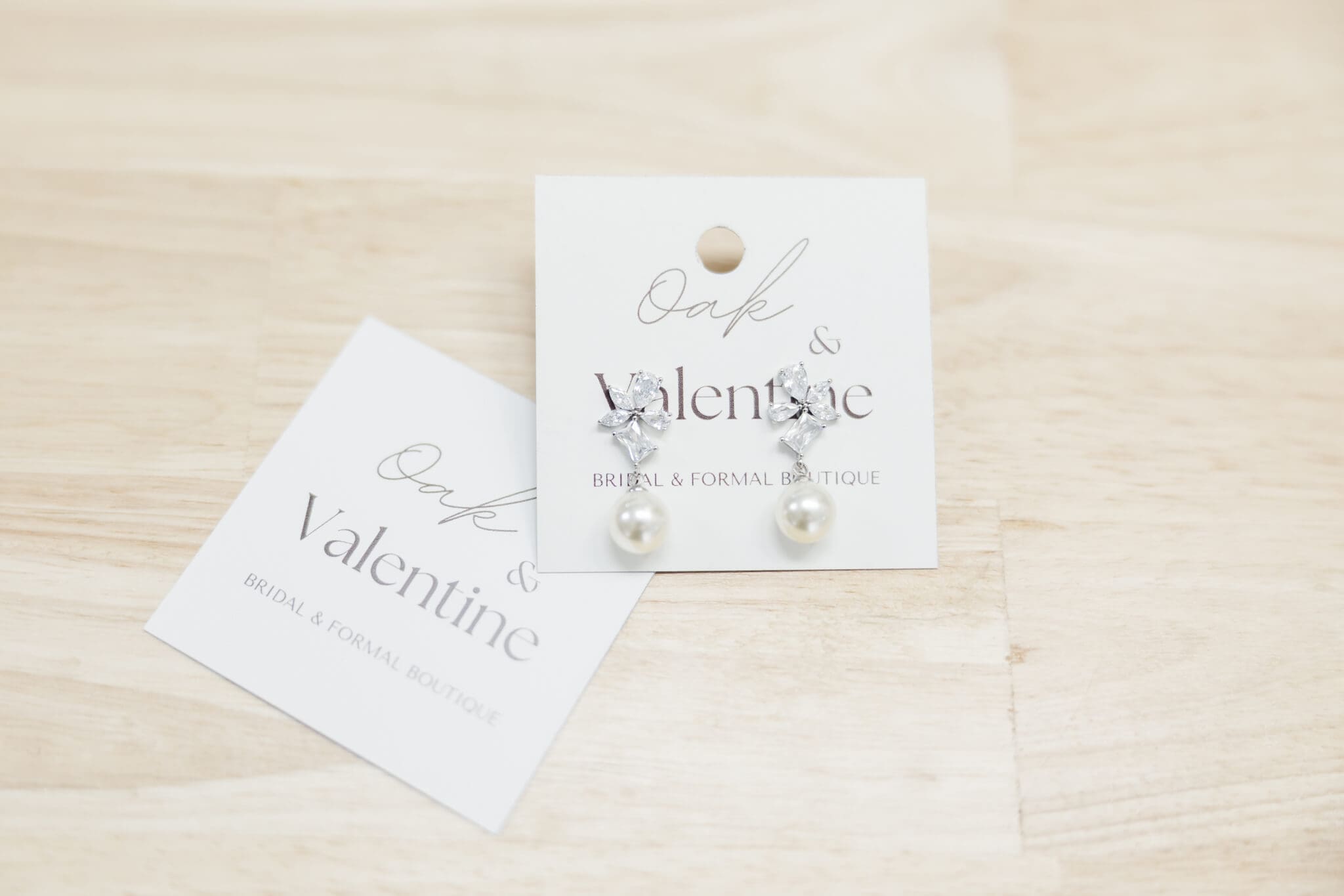 Earrings and business card belonging to bridal dress shop in Rockhampton, Oak and Valentine.