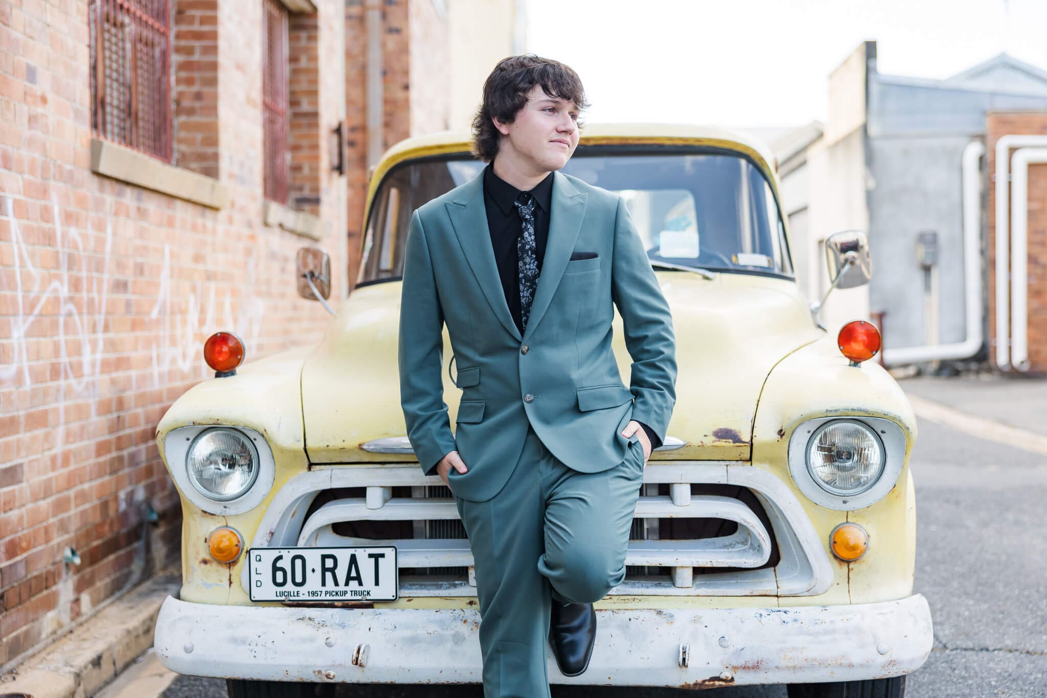 Portrait of a high school senior posing for his school formal photos in front of an old holden ute.