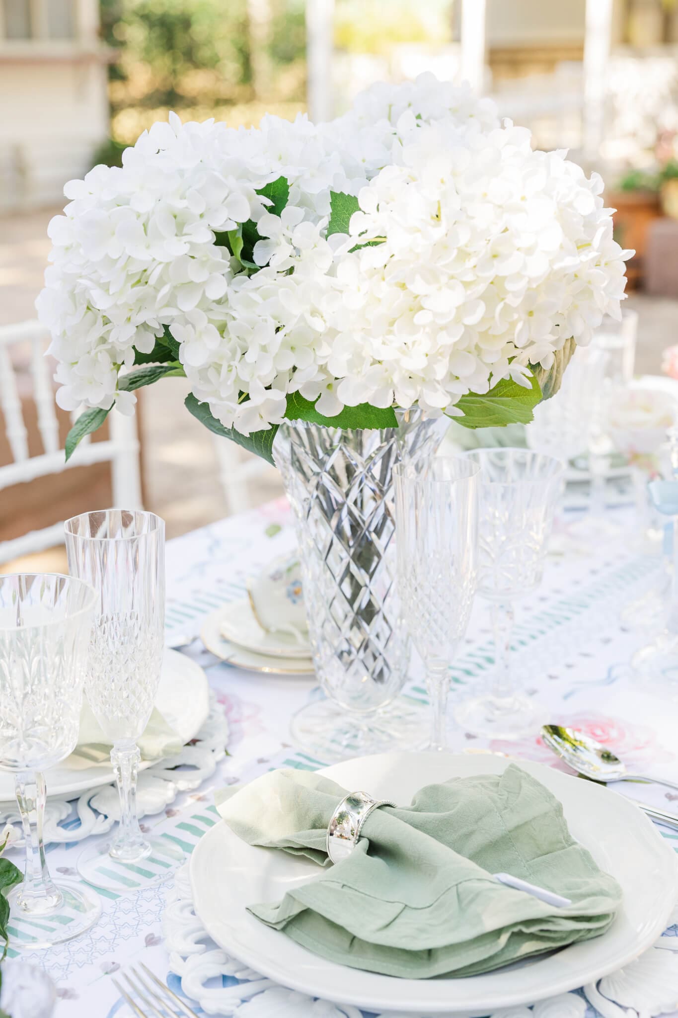 Detail shot of some table wear for a branding session including a vase of flowers, a green napkin held by a silver napkin ring and glass wine drink ware.