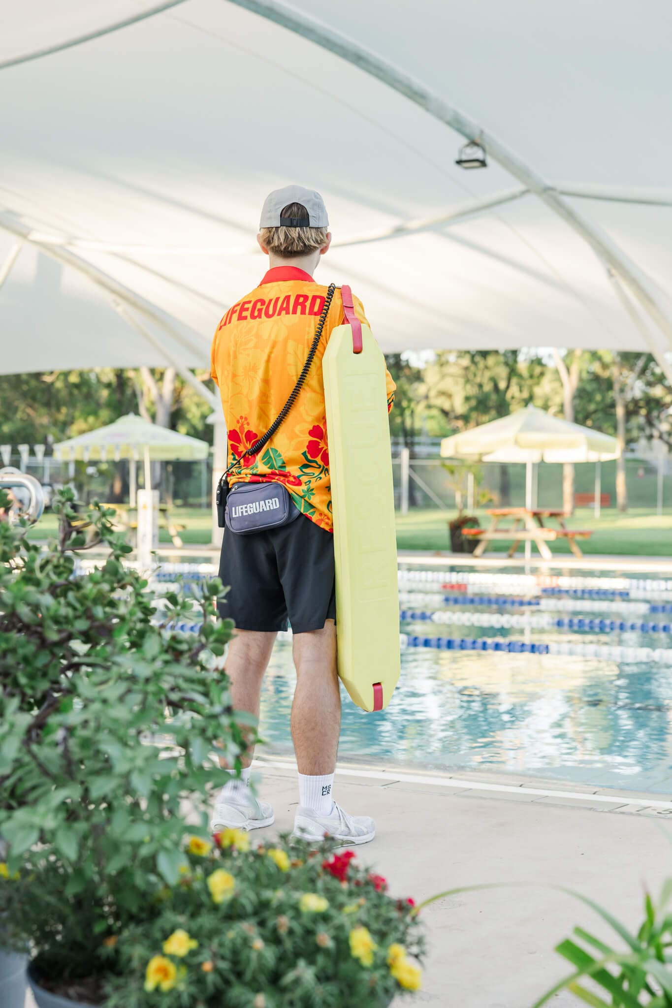 Detail shot of a lifeguard looking away from the camera towards a large Olympic sized pool.