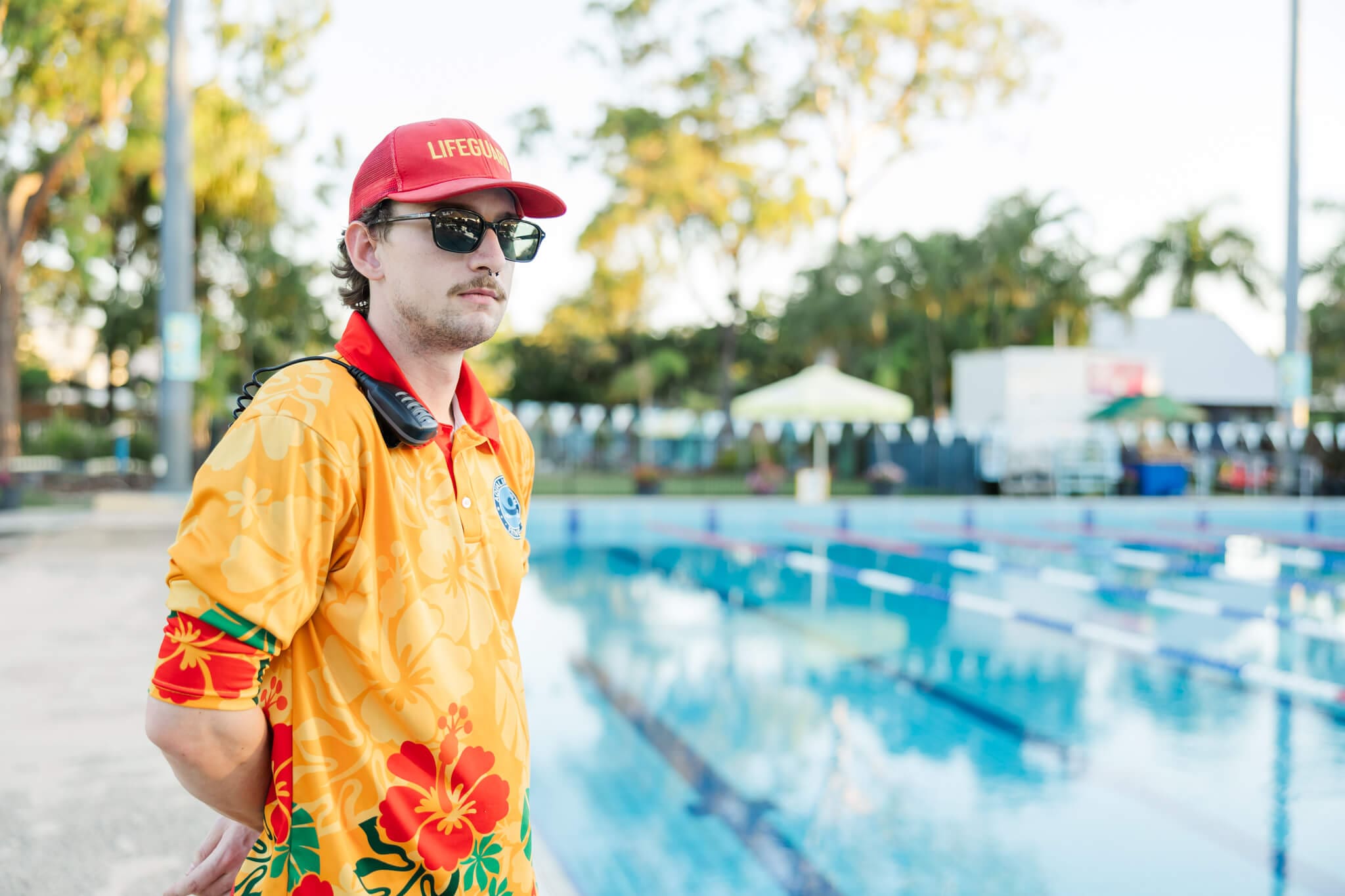 A website friendly image for a business featuring a a life guard looking over a large Olympic sized pool