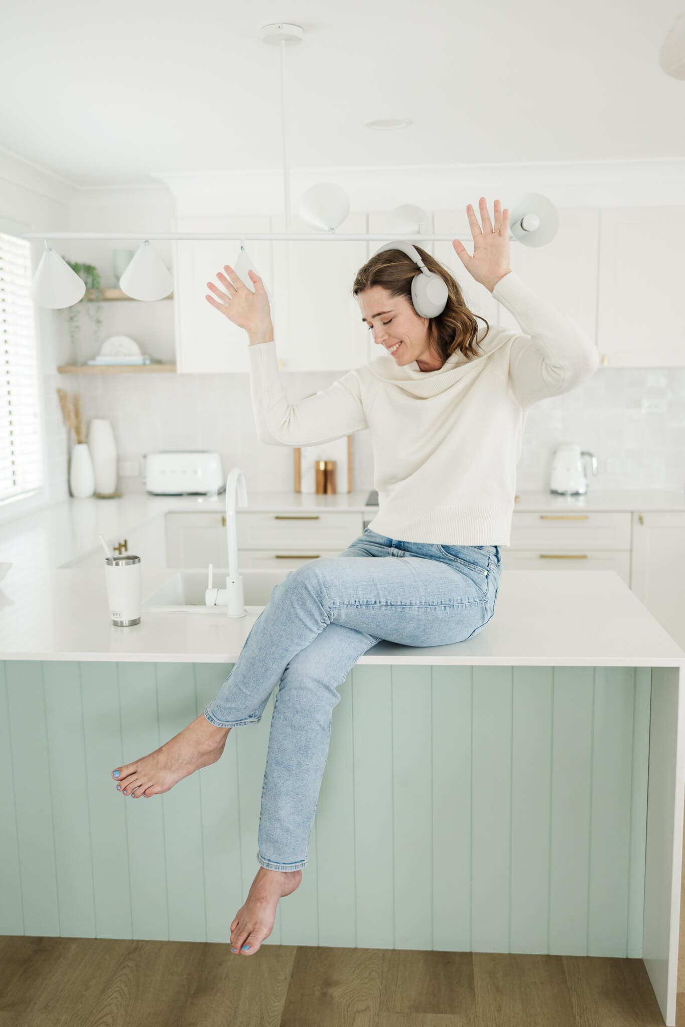 Woman dressed in a white top with headphones on, jiving to music while she poses for her branding session.