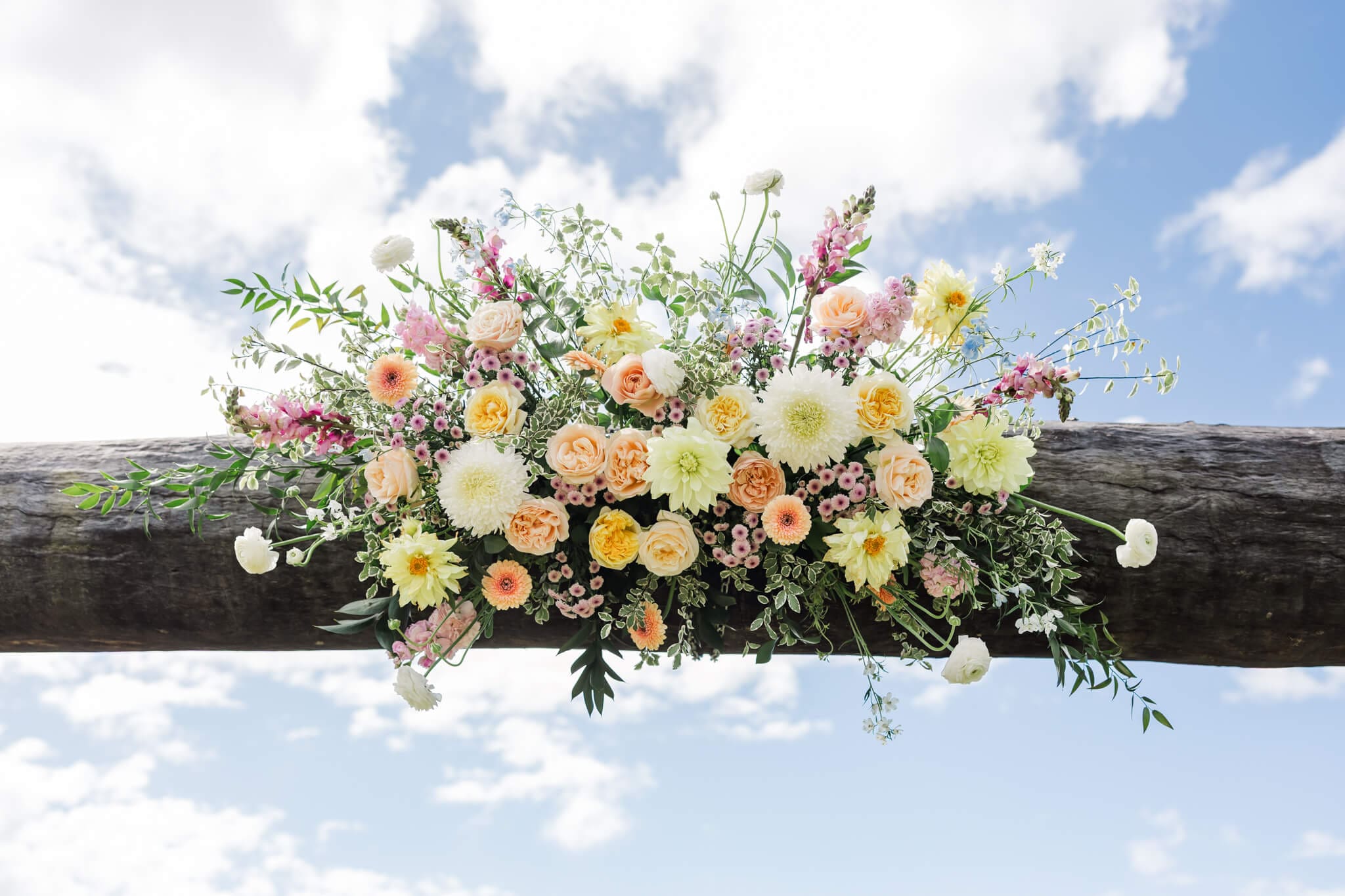 Stunning floral piece on a rail for a wedding ceremony consisting of pastels against soft greenery.