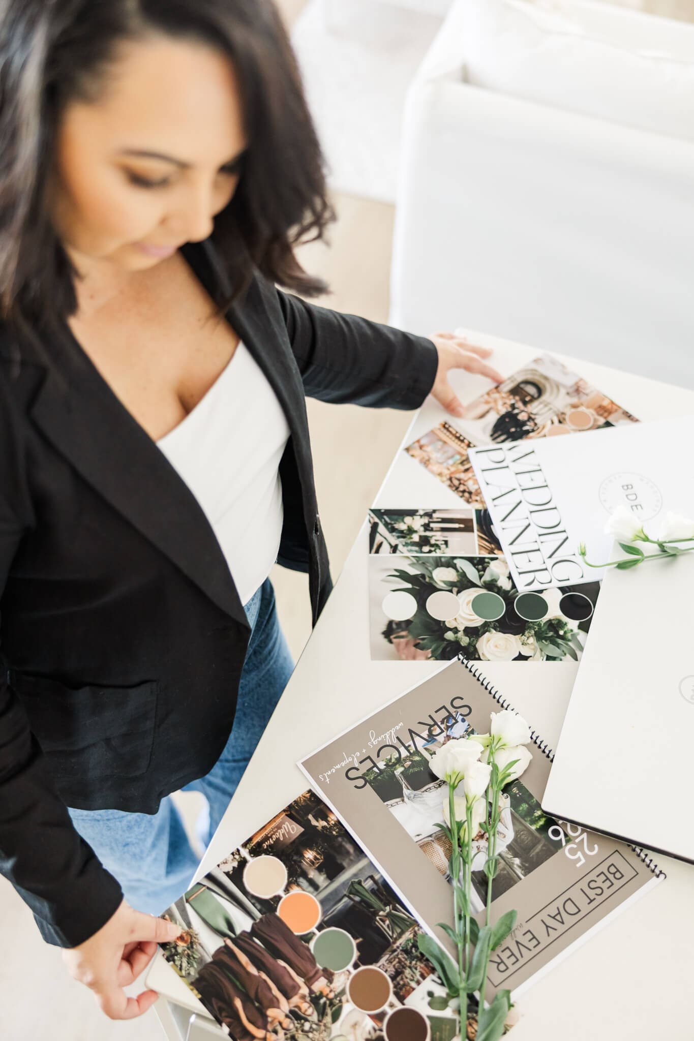 Detail shot of an event planner looking over her wedding brochures. She is dressed in a black jacket and blue jeans.