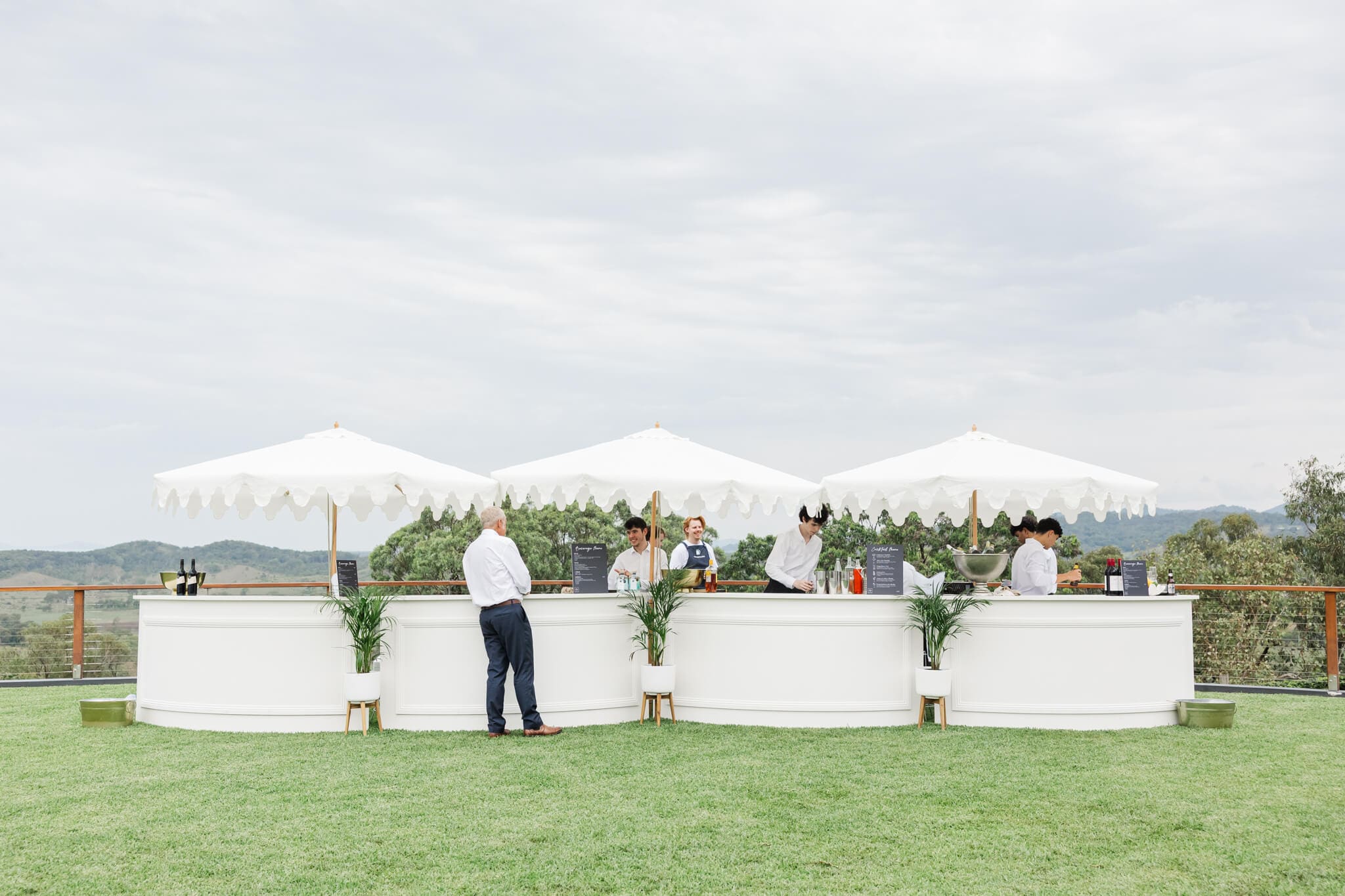 Outdoor pop up bar at a luxury events venue near Yeppoon. Consists of white umbrellas, white counters all on a carefully manicured lawn.