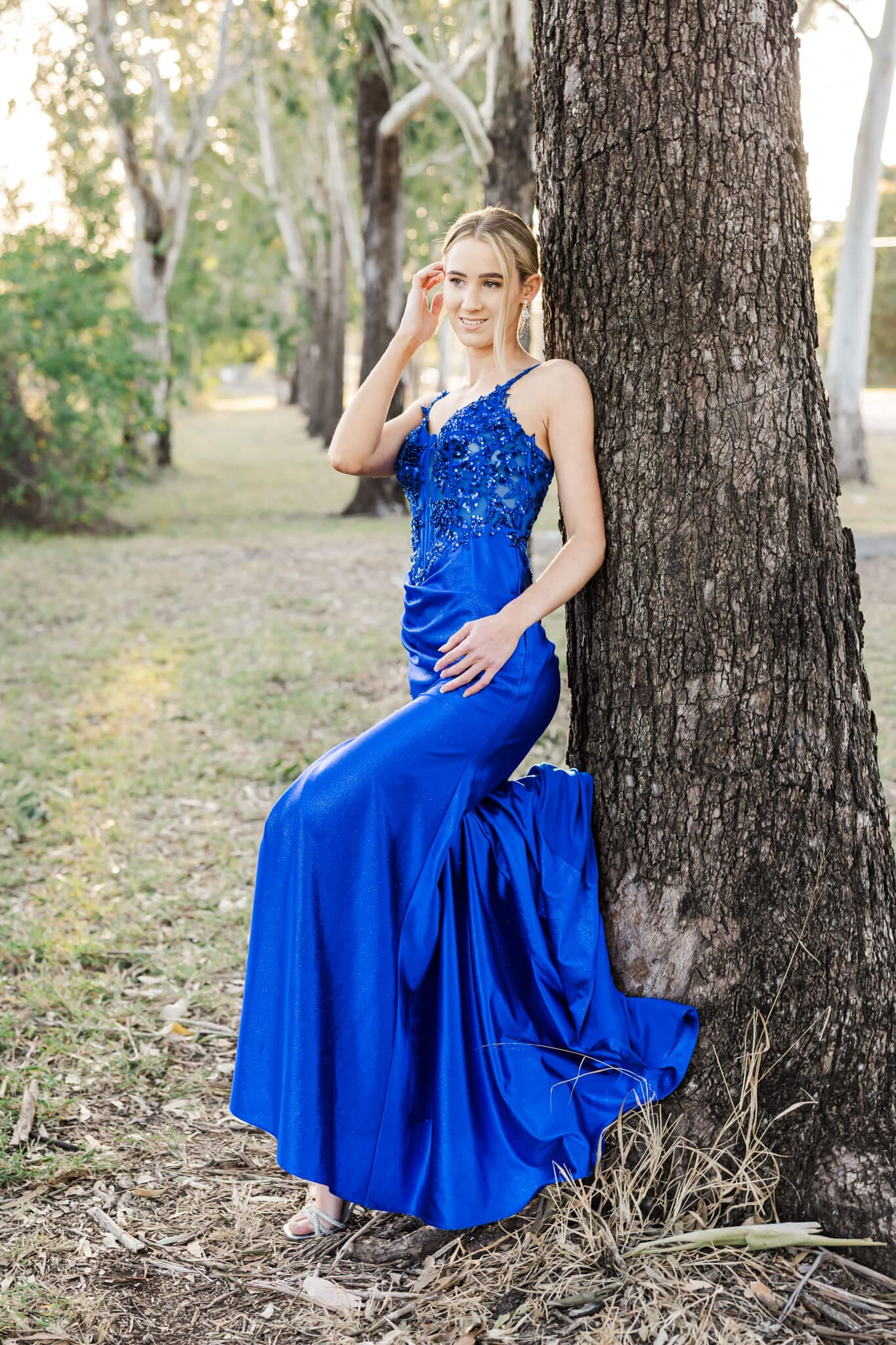 Beautiful graduate dressed in a blue gown, posing for her pre formal photography session.
