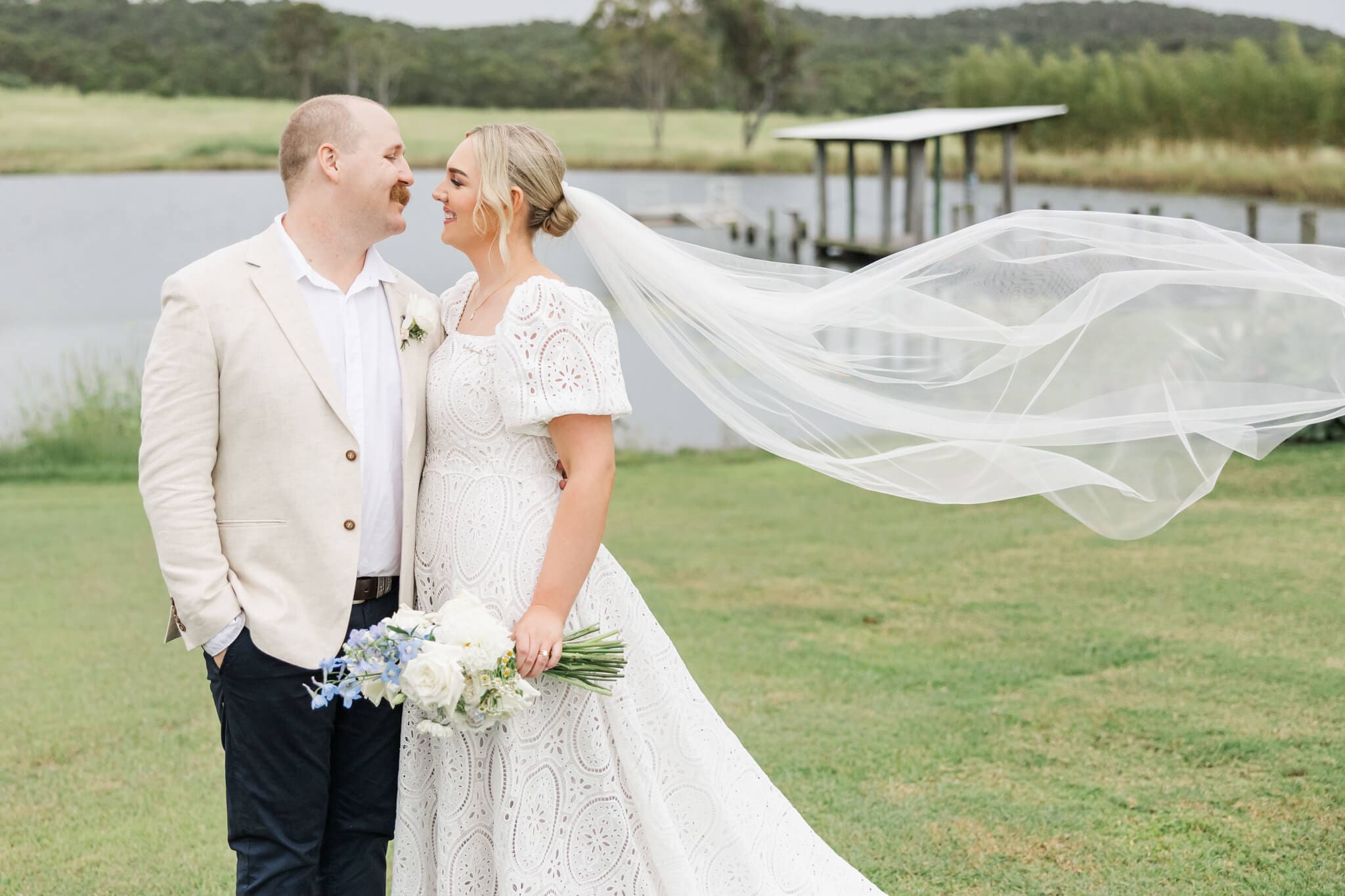 Bride and groom pose for a wedding portrait by a lake at a wedding venue near Yeppoon.