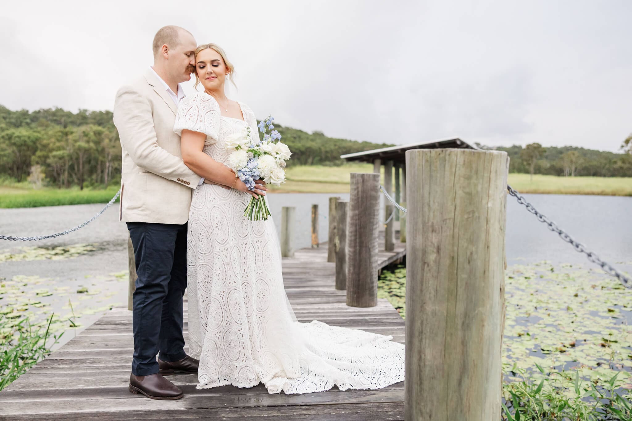 Bride and groom share a close moment on  a jetty by a lake at a wedding venue near Yeppoon.
