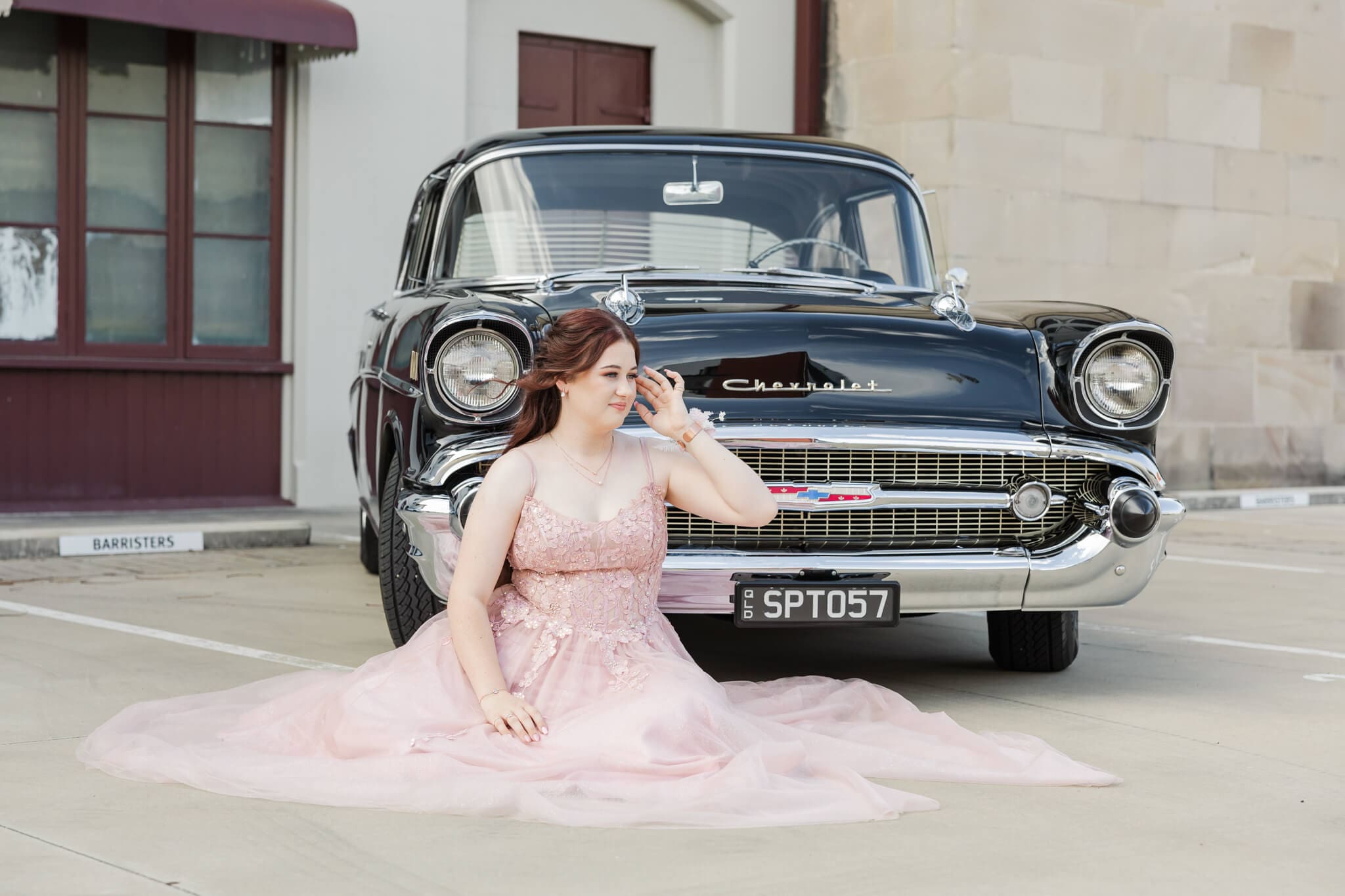 High school senior poses for her formal photos, seated on the ground in her pink gown. Image by Julie-Anne Photography.