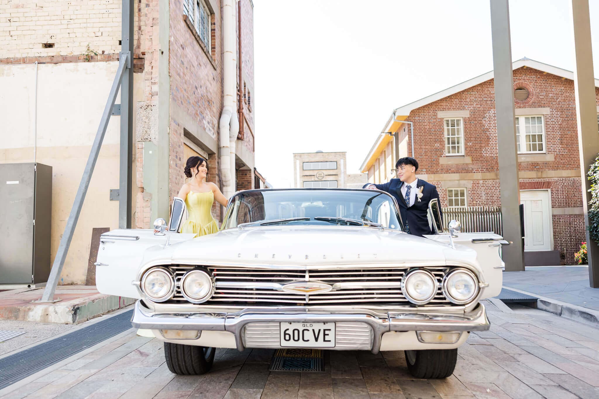 Formal graduates and their cream car hire in Rockhampton, posing for their formal photos.