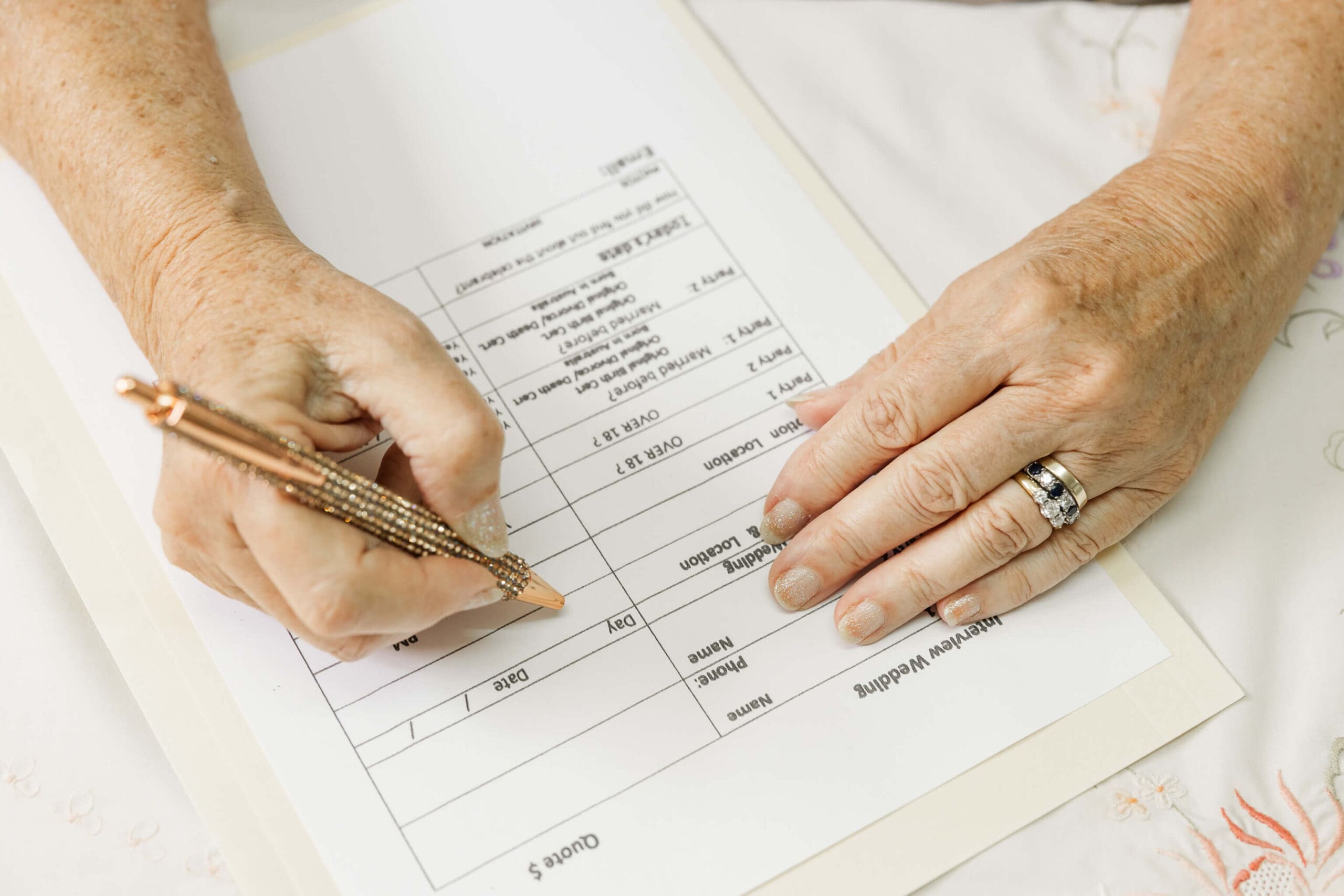 Hands of a Rockhampton and Yeppoon marriage celebrant writing an application to be married.