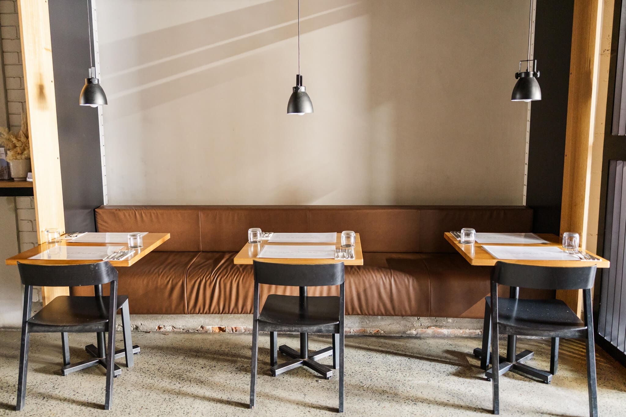 Headricks Lane, a restaurant in Rockhampton, with a modern industrial vibe. Showcasing here 3 table settings with a lamp overhanging each one.