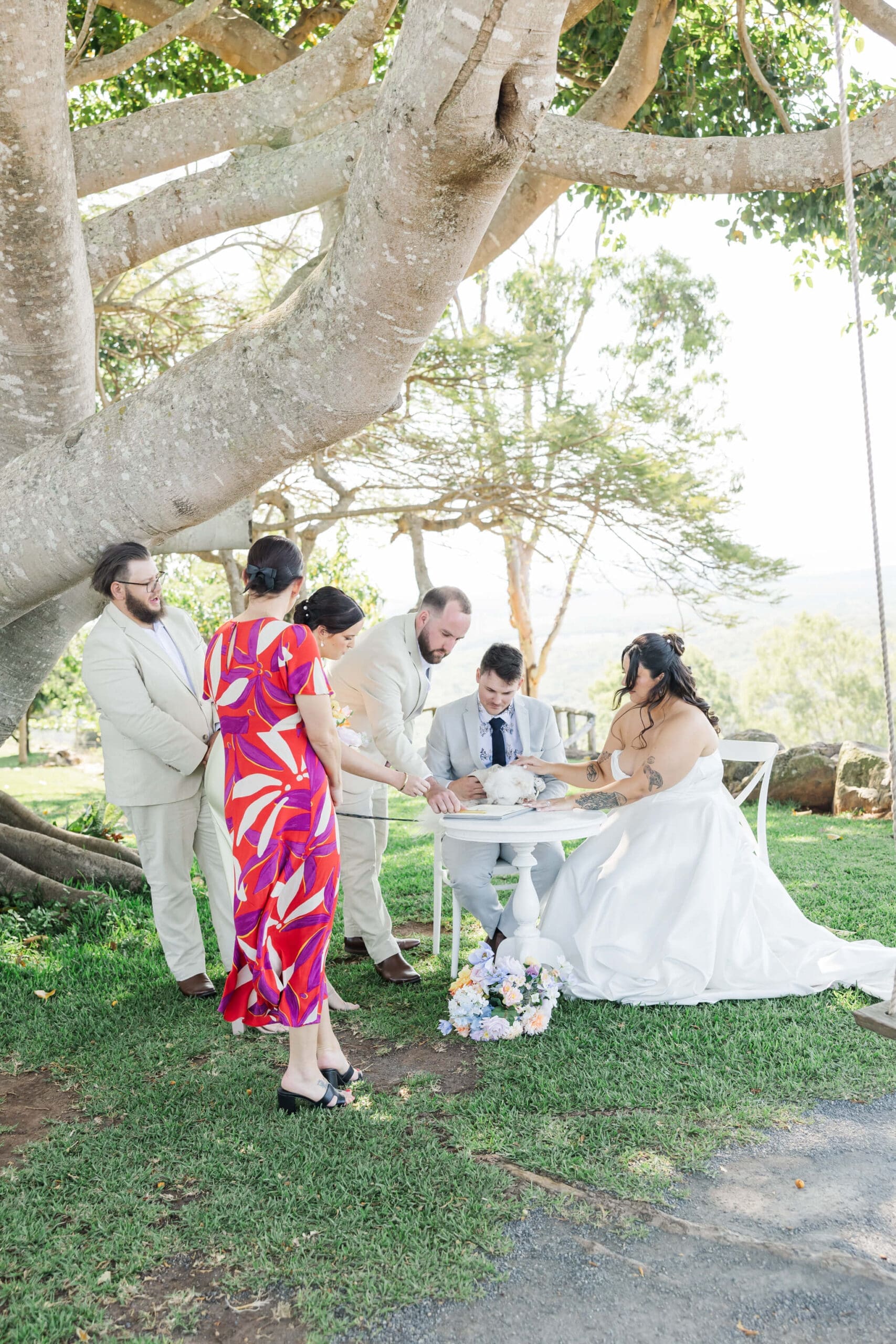 Central Queensland marriage celebrant assisting a bride and groom sign the register, at a wedding venue near Yeppoon.