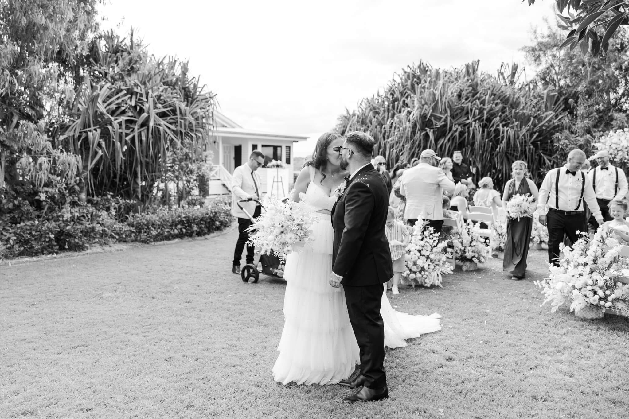 Bride and Groom share a kiss. Groom dressed in a suit purchased from Rockhampton.