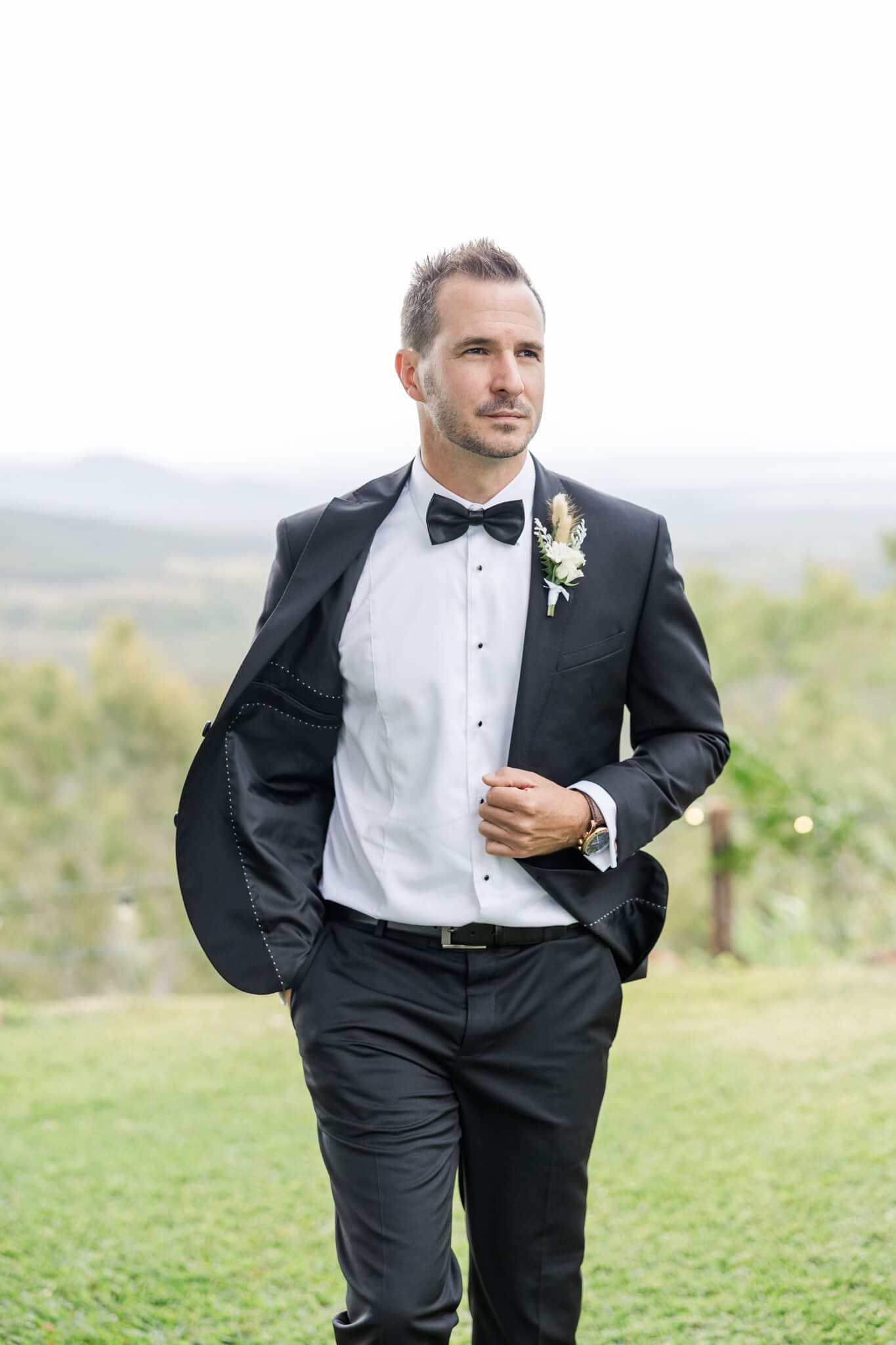 Groom dressed in a black Rockhampton suit, walking with it unbuttoned.