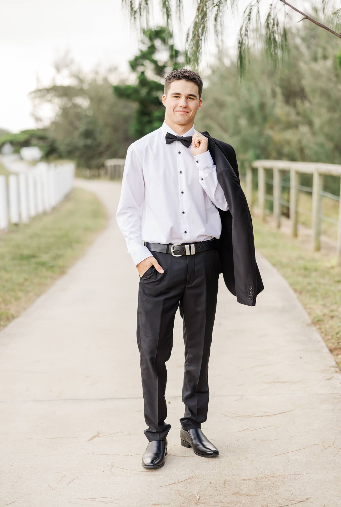High school graduate walking towards camera wearing an outfit from Stewart's, a store that sells suits in Rockhampton.