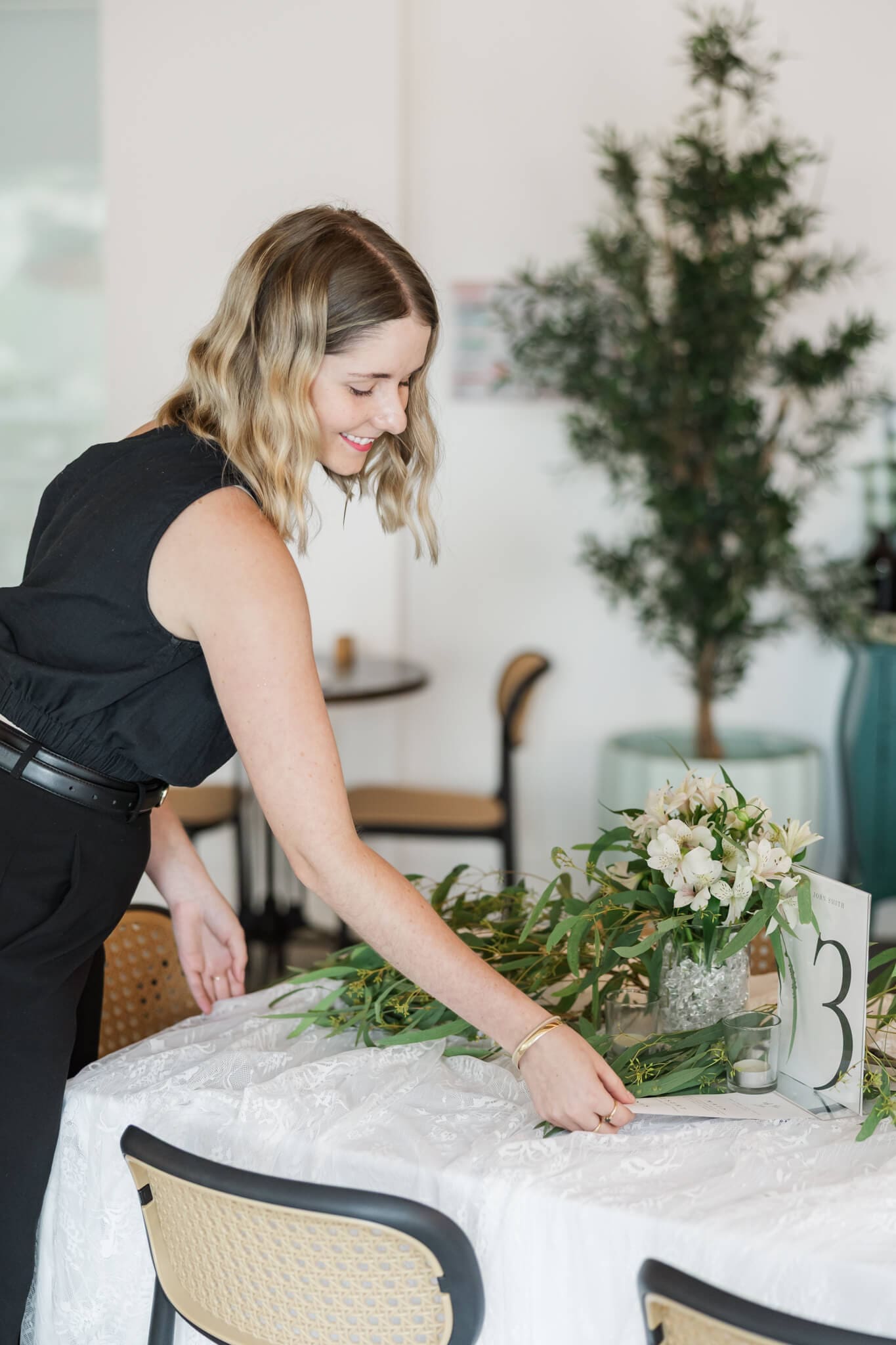 Shelby from Timber and Lace Wedding Coordination, adjusts a table she is styling, captured by Julie-Anne Photography.