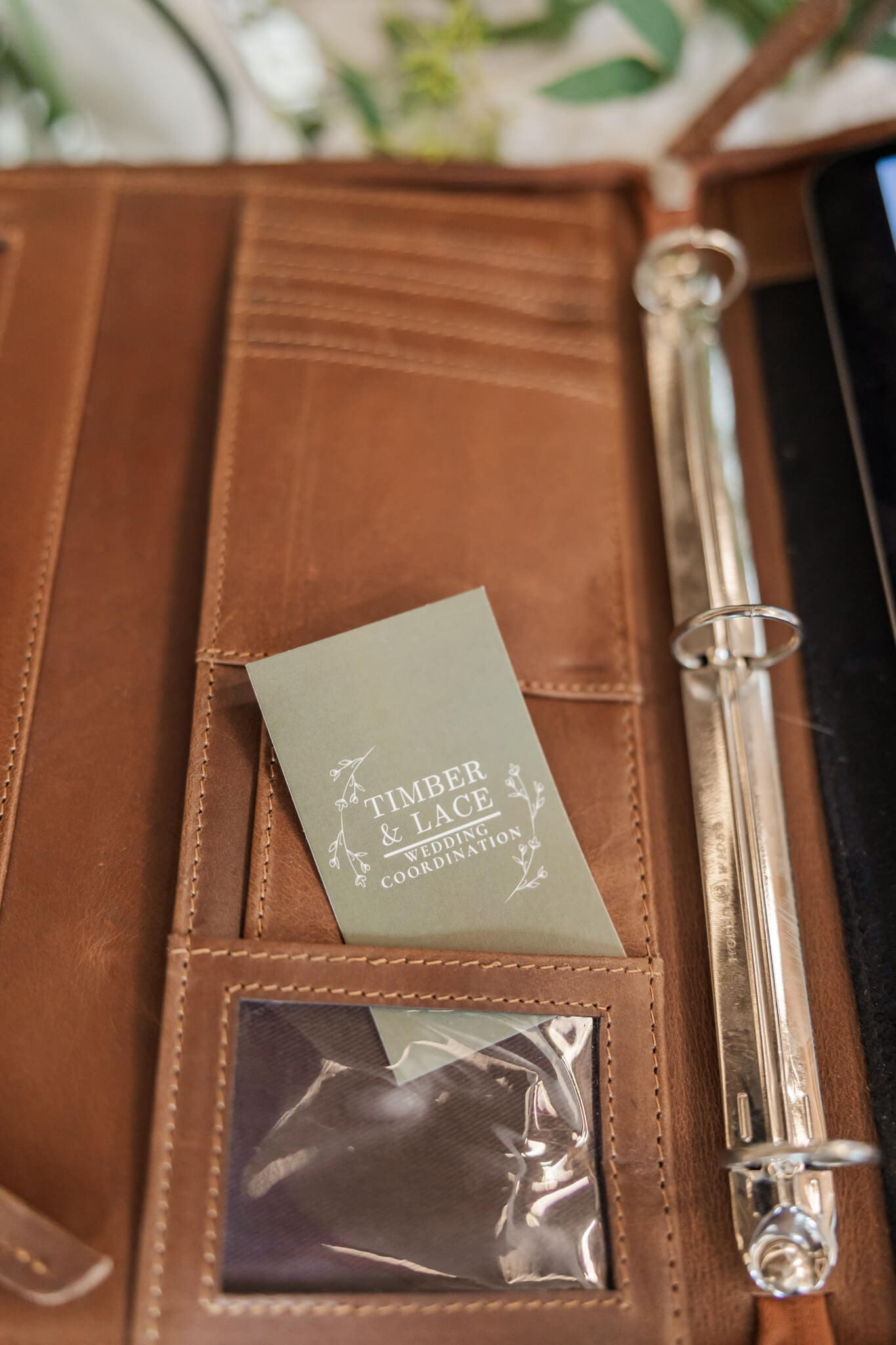 Business card for Timber and Lace Coordination, sitting in a leather wedding planner folder.
