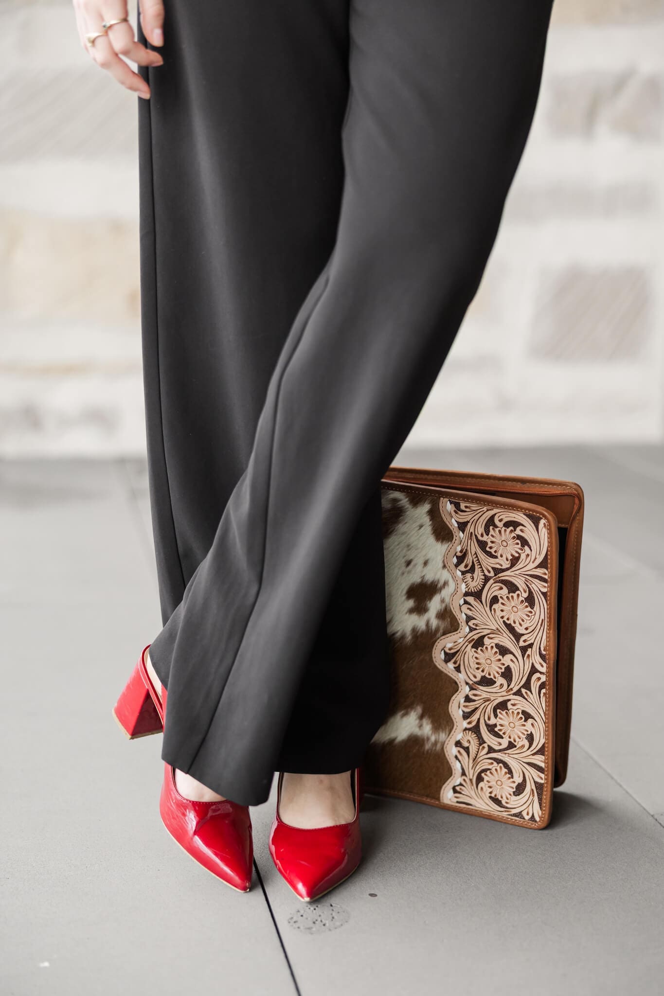 Photo of a pair of woman's legs, standing, crossed feet, wearing a pair of red high heels.