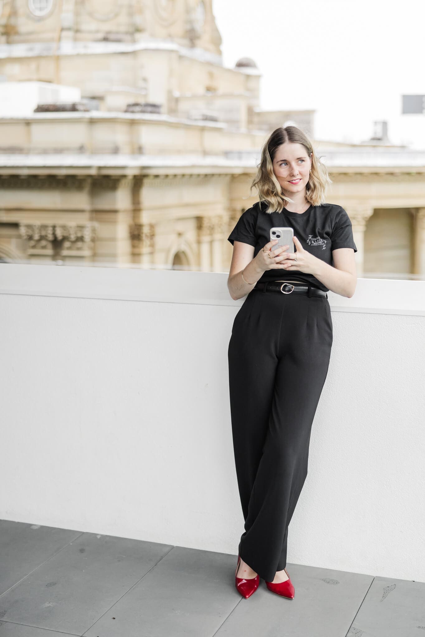Shelby, a Rockhampton wedding planner, stands with her phone, at a wedding venue.