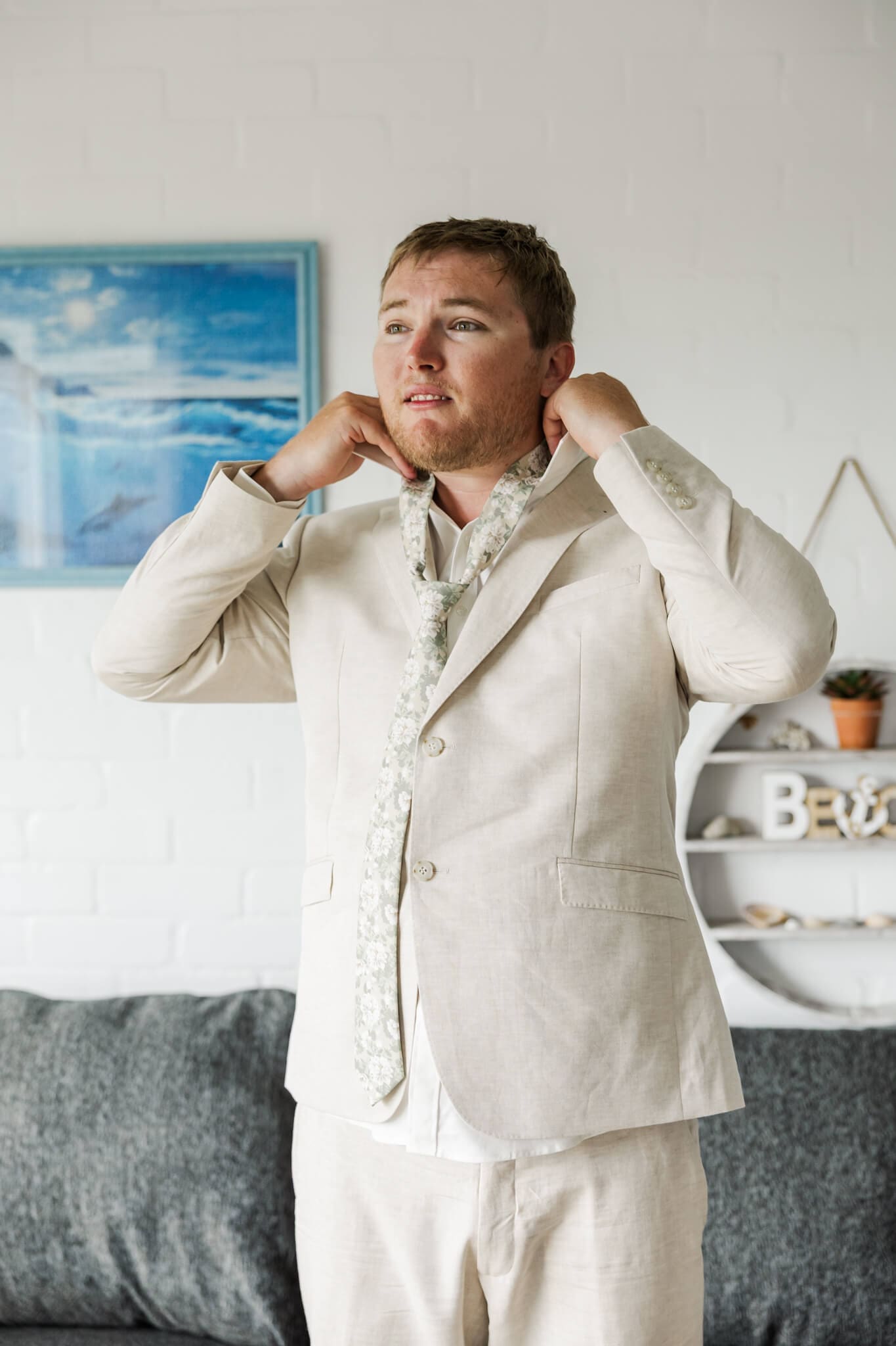 Groom adjusts his collar as he puts his tie on, getting ready at wedding venue The Haven Yeppoon.