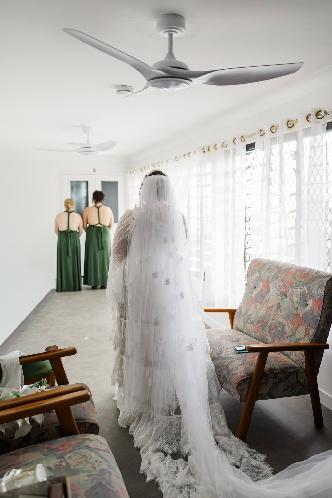 First look for a bride for her bridesmaids. 2 bridesmaids have their backs turned as the bride approaches.