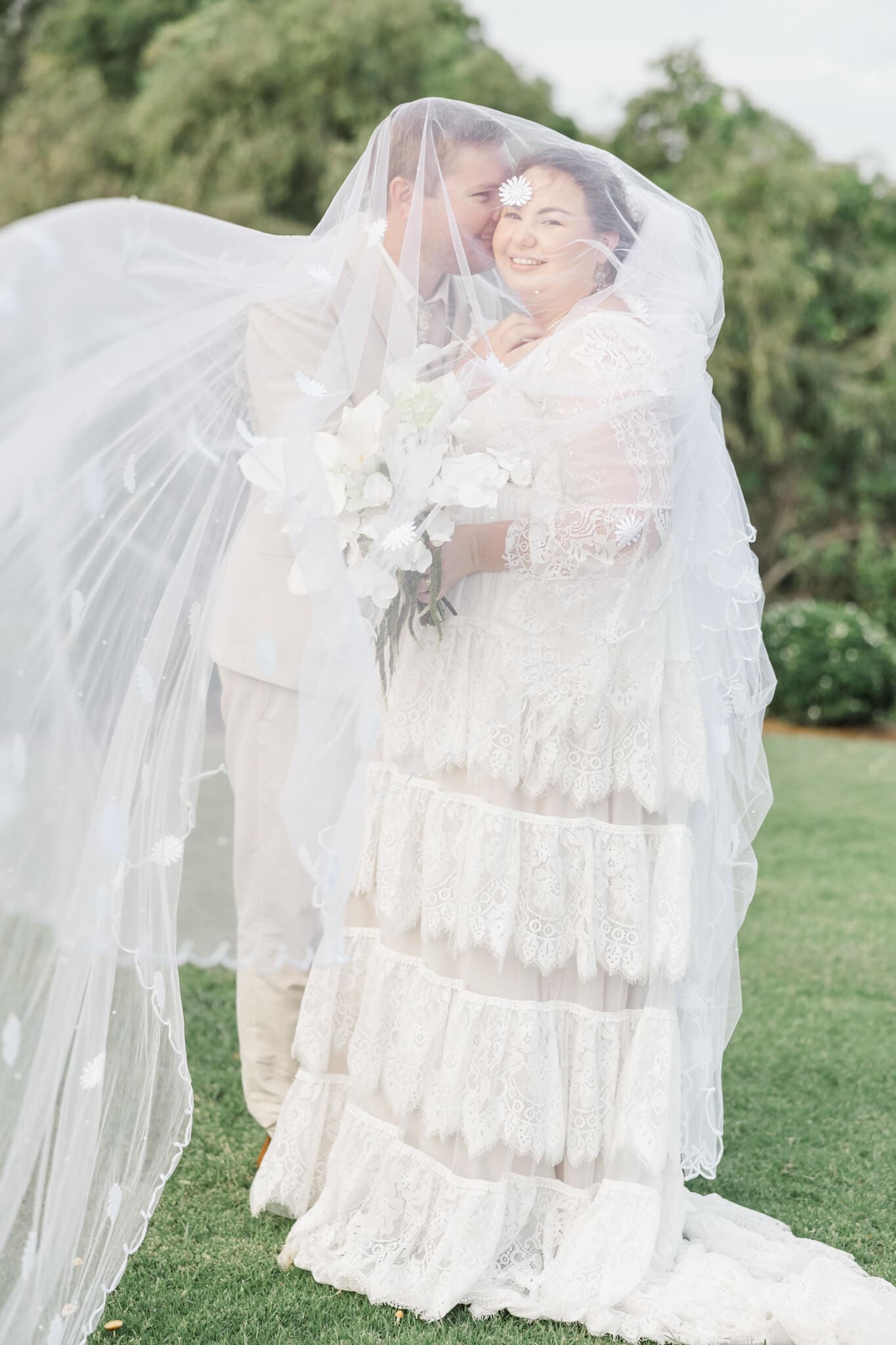 Black and white image of groom kissing the bride under her veil. Located at The Haven Yeppoon.