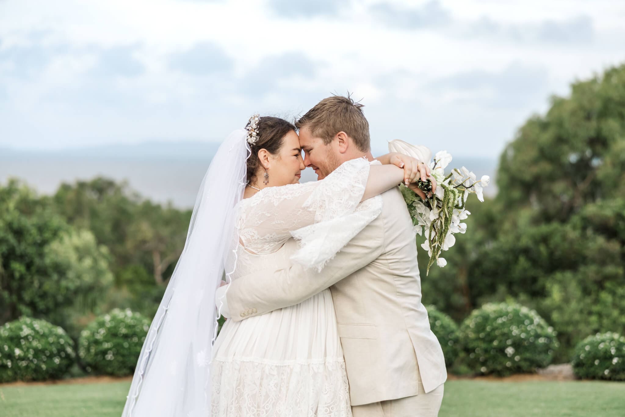 Bride and Groom share a quiet moment in each others arms at The Haven Yeppoon, with the ocean in the background.