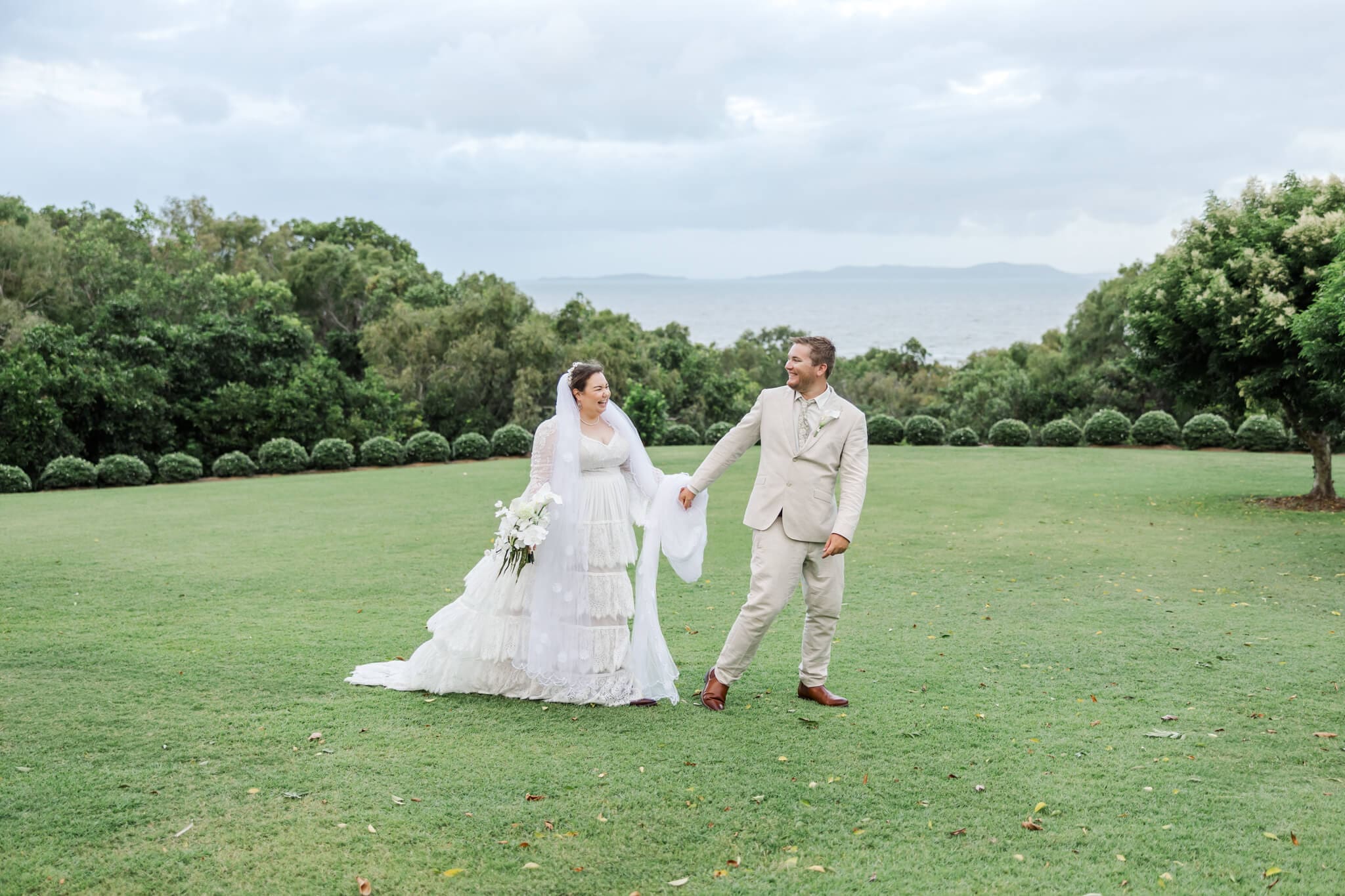 Bride and groom walk across the lawn at wedding venue The Haven Yeppoon, near Emu Park.